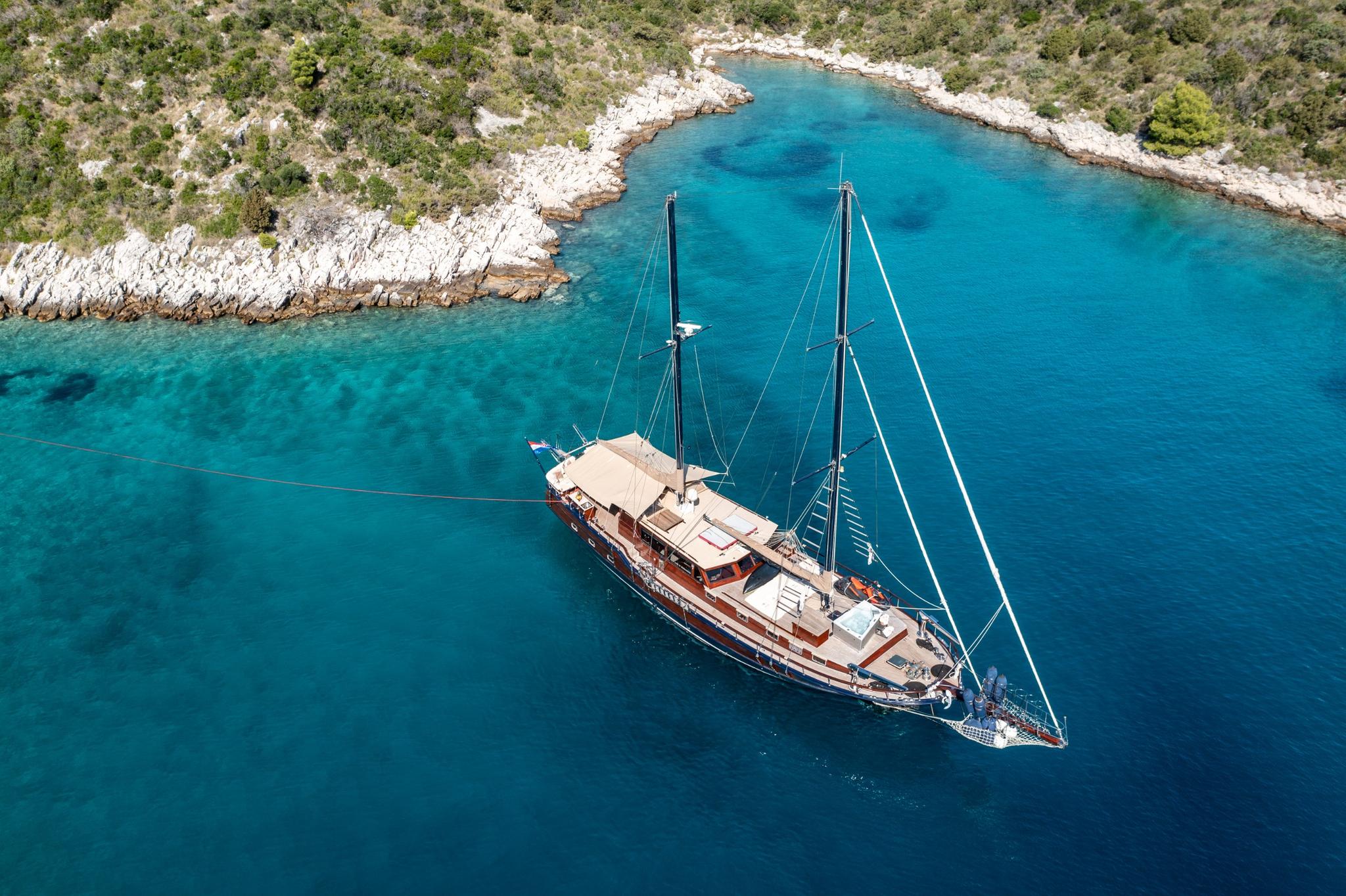 aerial view of traditional wooden gulet yacht anchored in pristine turquoise Mediterranean bay