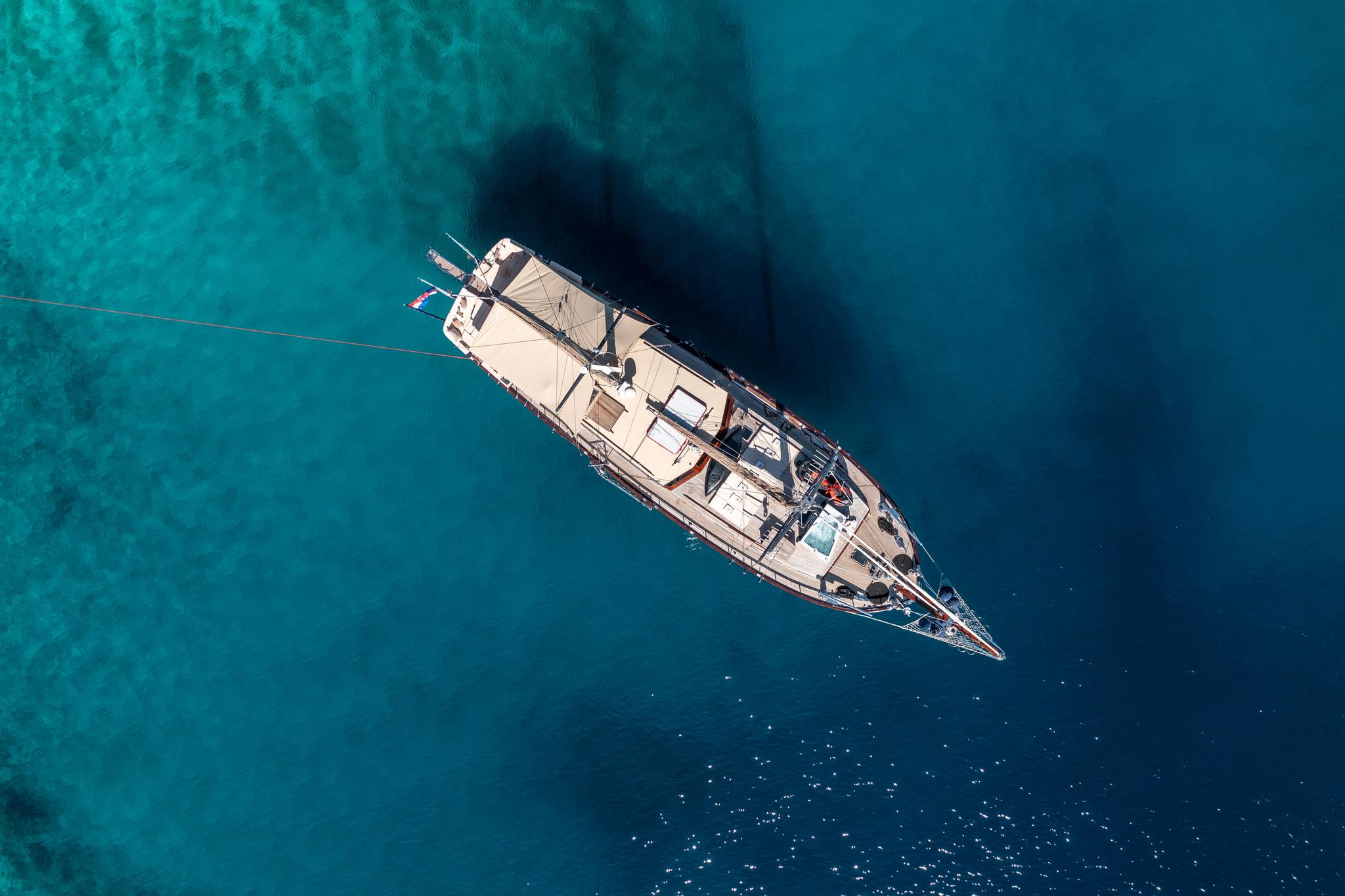 aerial view of traditional gulet yacht at anchor in crystal clear turquoise Mediterranean waters