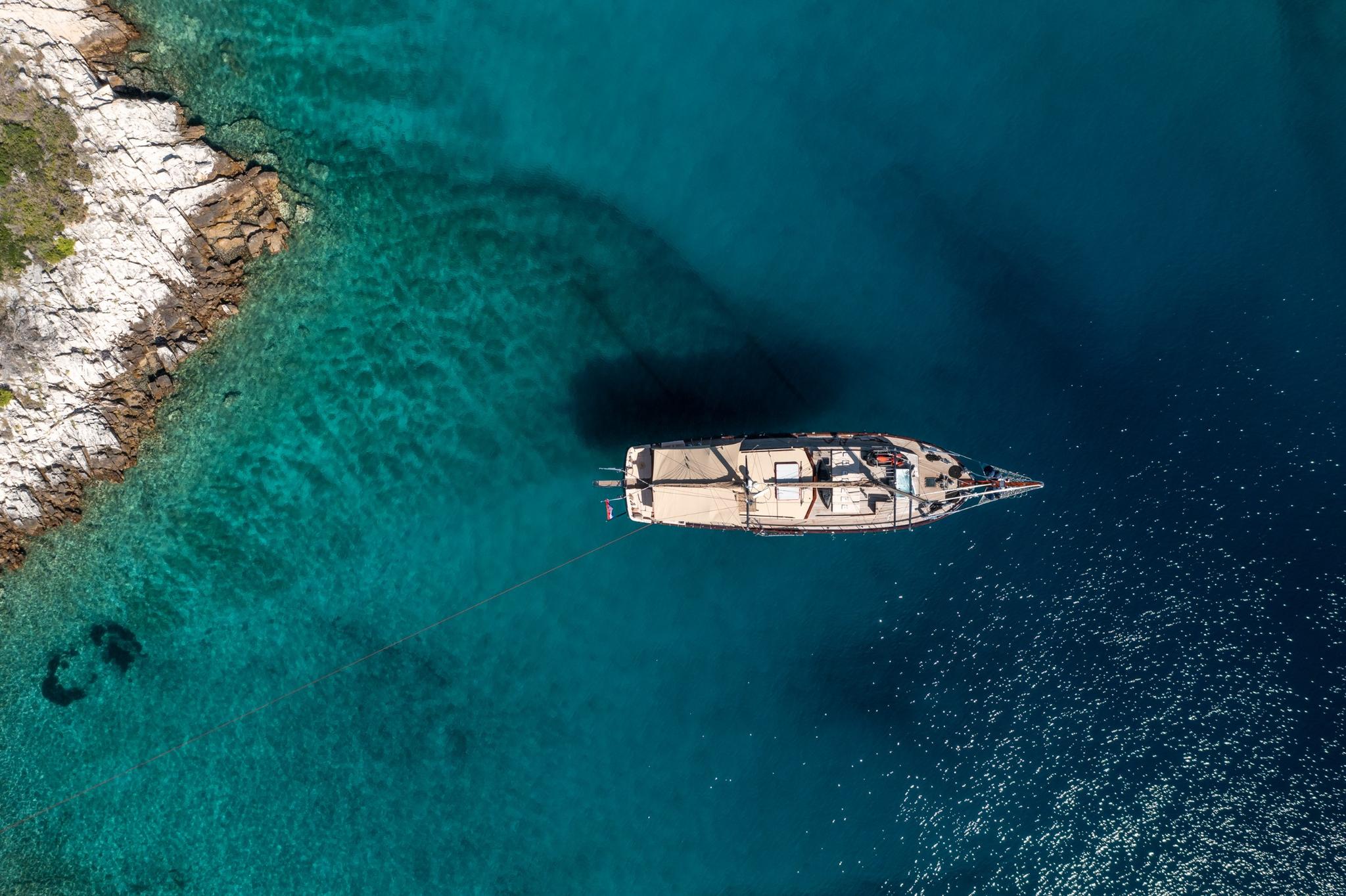 aerial view of traditional wooden gulet yacht anchored in crystal clear turquoise waters