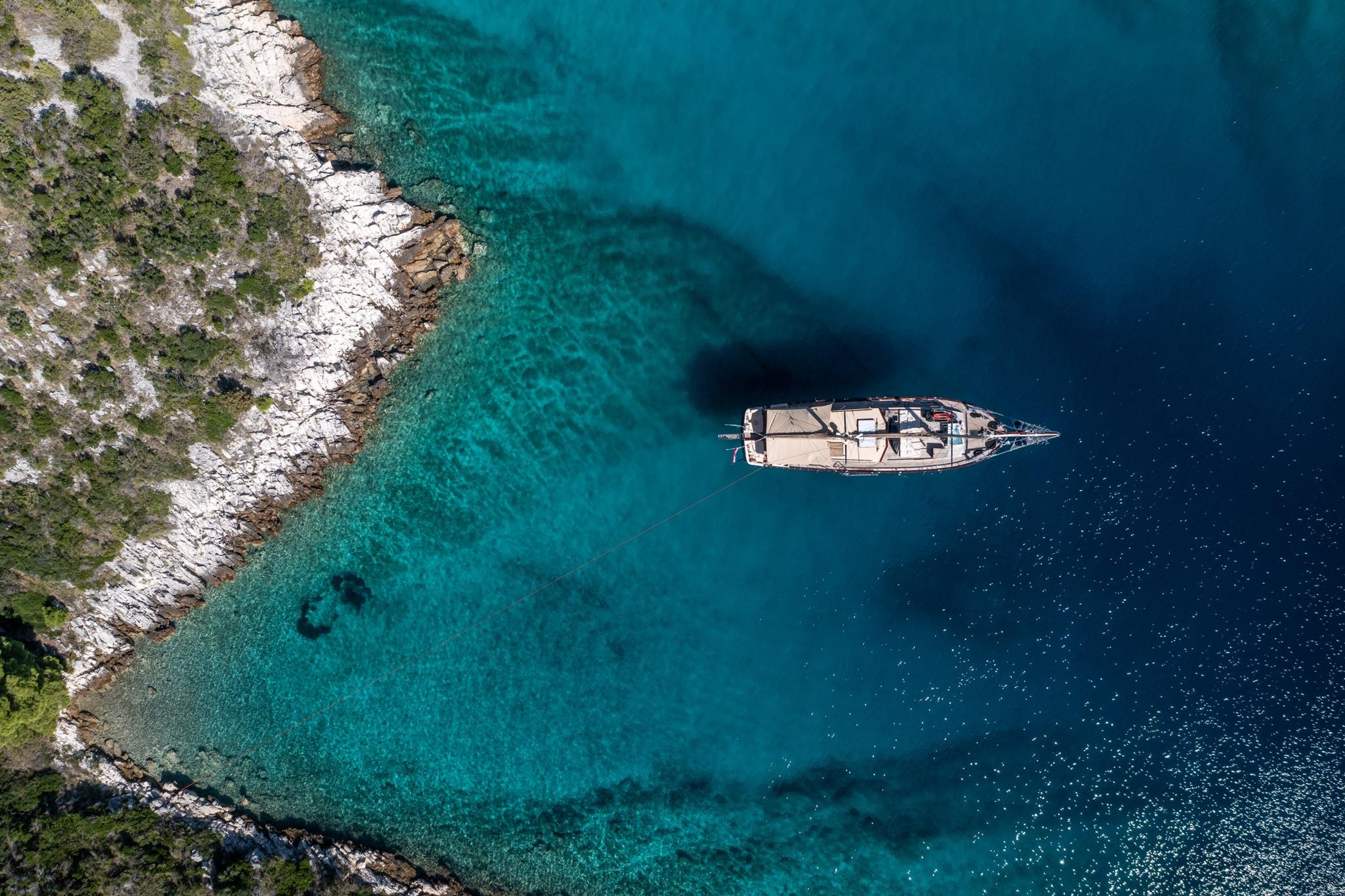 aerial view of luxury gulet yacht anchored in crystal clear turquoise Mediterranean bay