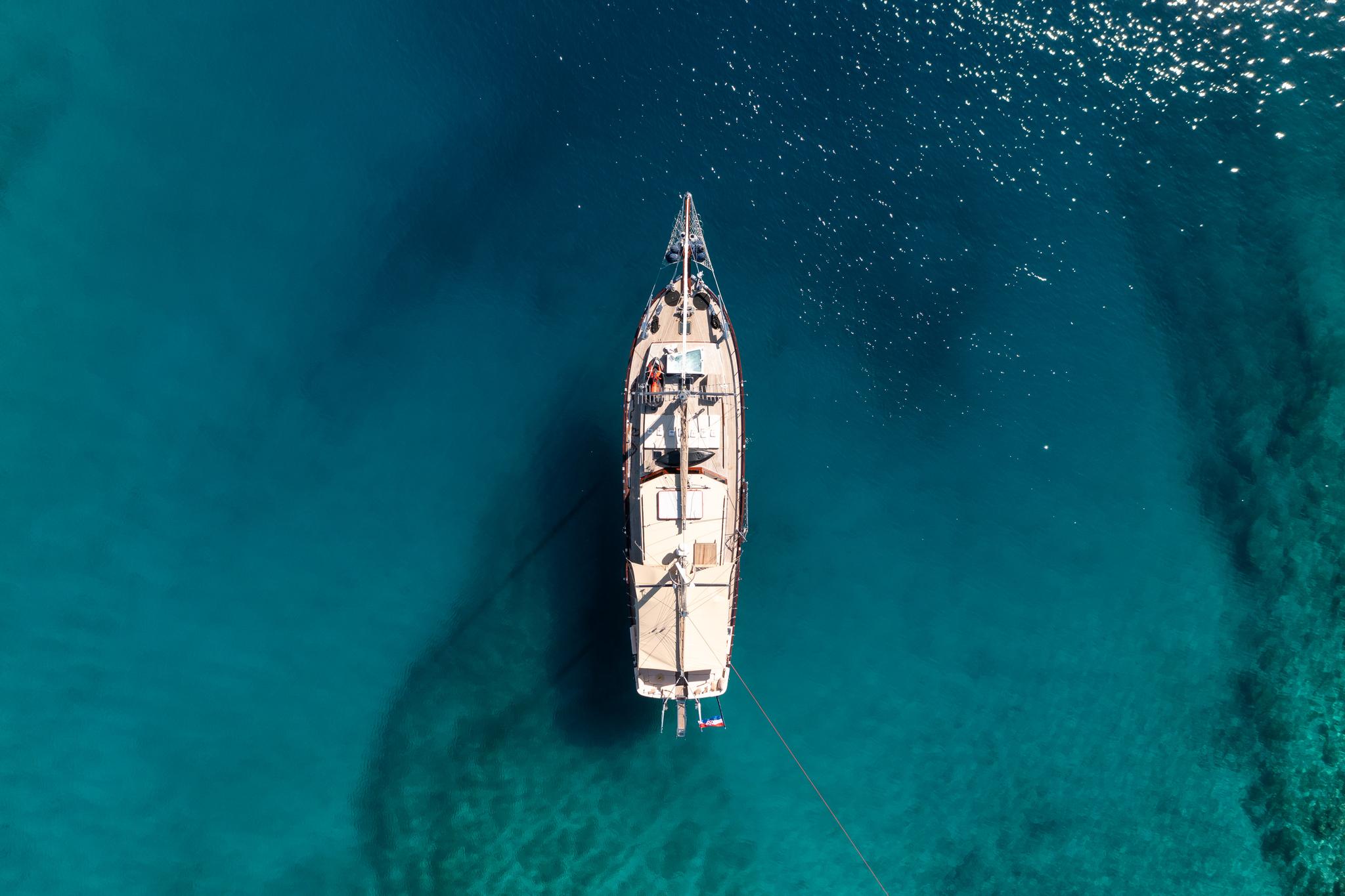 aerial view of wooden gulet yacht anchored in crystal clear turquoise Mediterranean waters