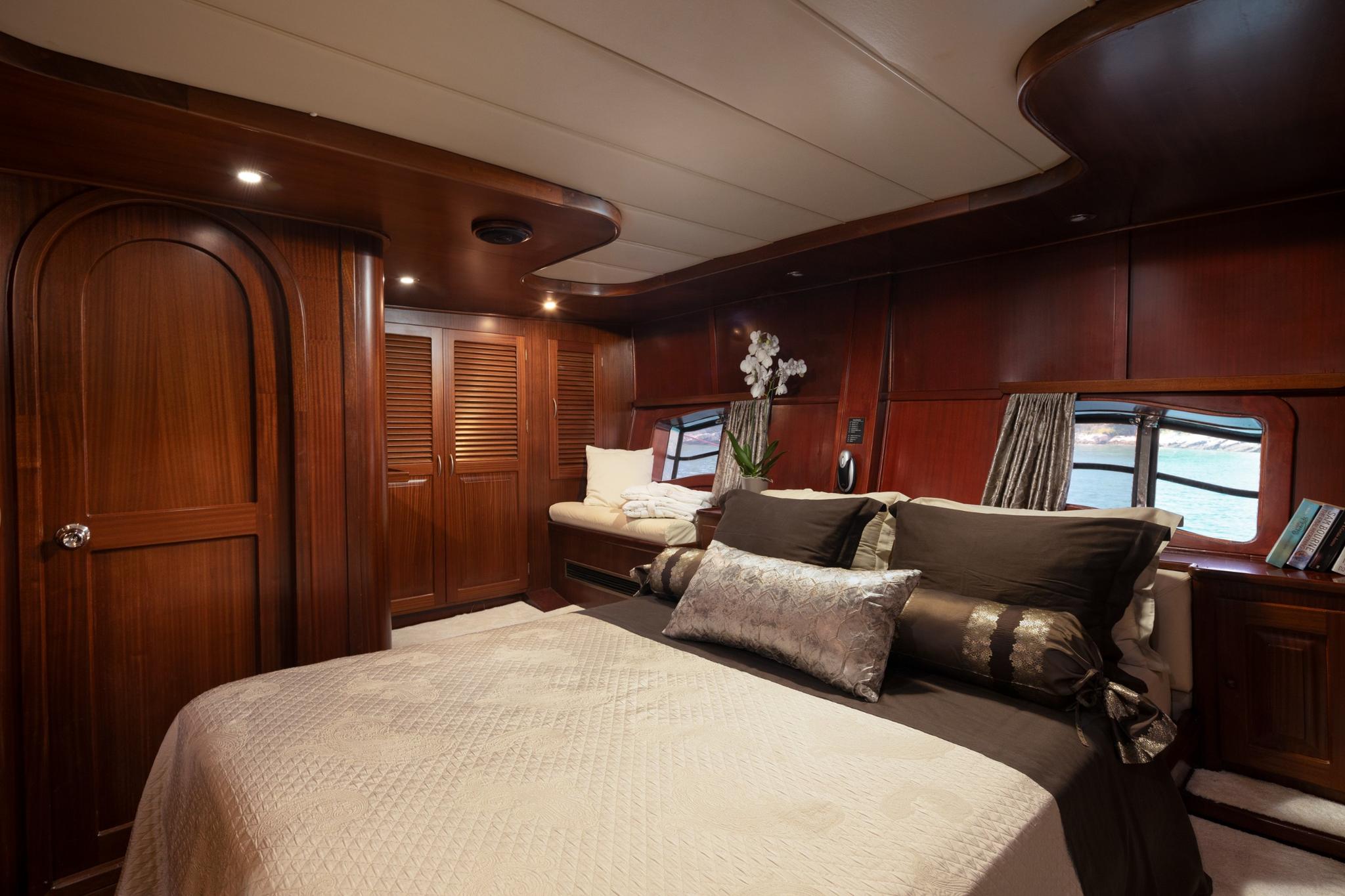 luxury yacht master cabin featuring king bed, dark wood paneling, and panoramic windows