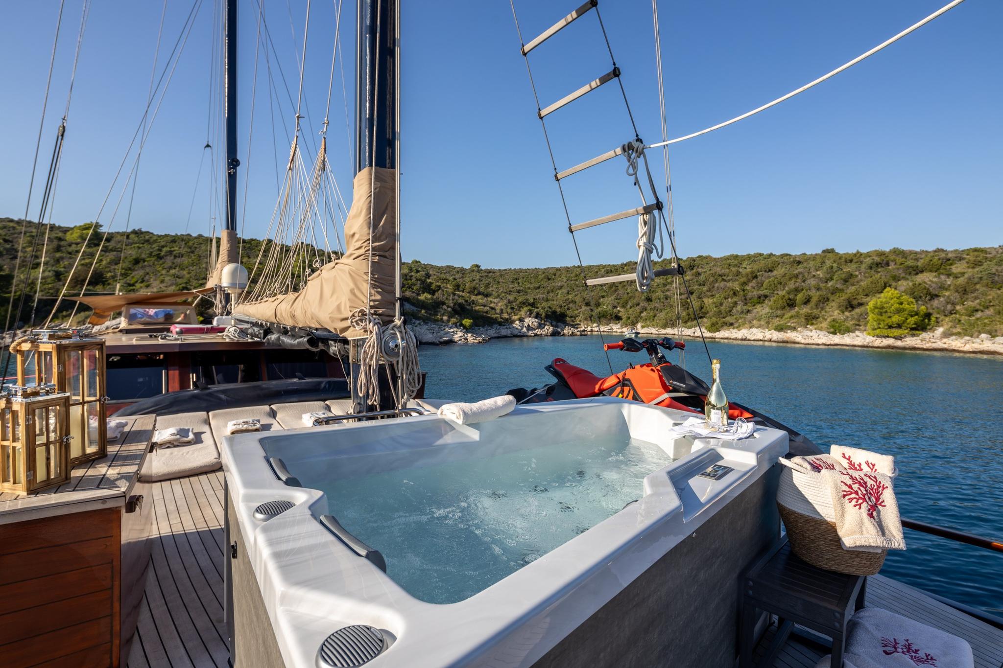 white rectangular jacuzzi on yacht deck with jet skis and water toys in secluded bay