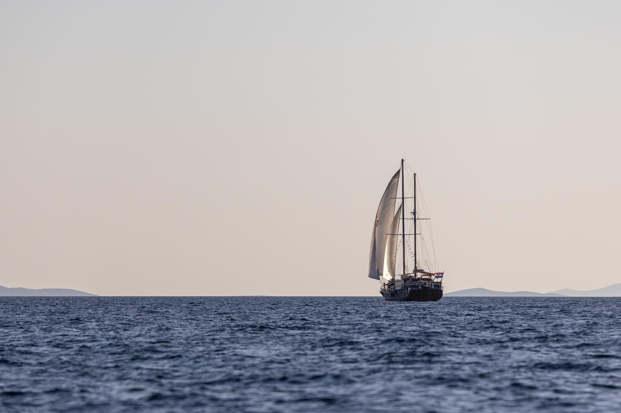 traditional sailing yacht with white sails deployed cruising on blue Mediterranean waters