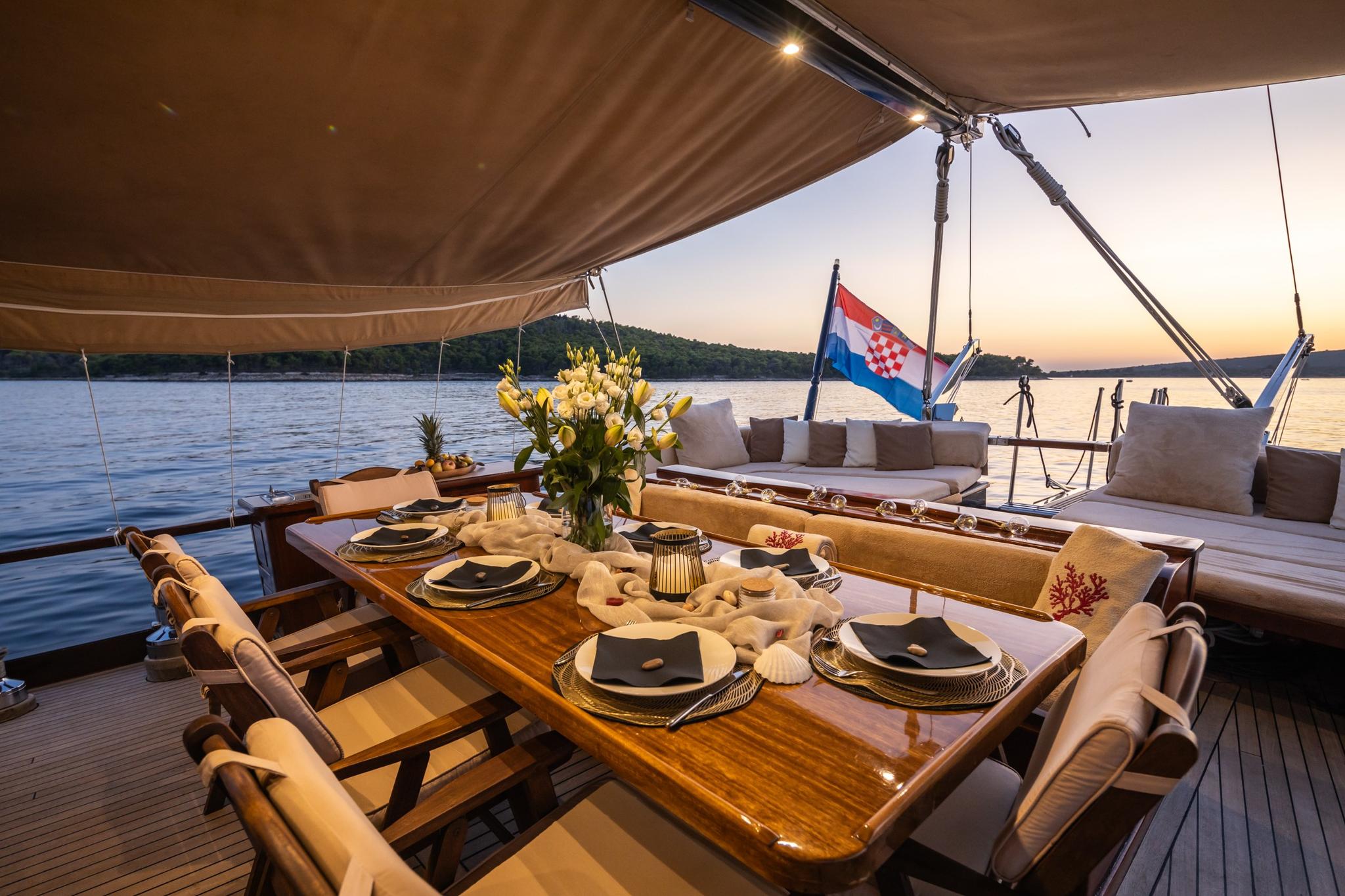 elegant outdoor dining table set with plates and glasses on yacht deck at sunset