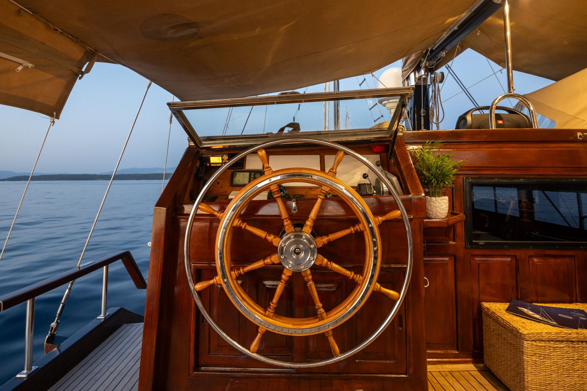 gulet helm station featuring traditional wooden steering wheel with brass center and navigation instruments
