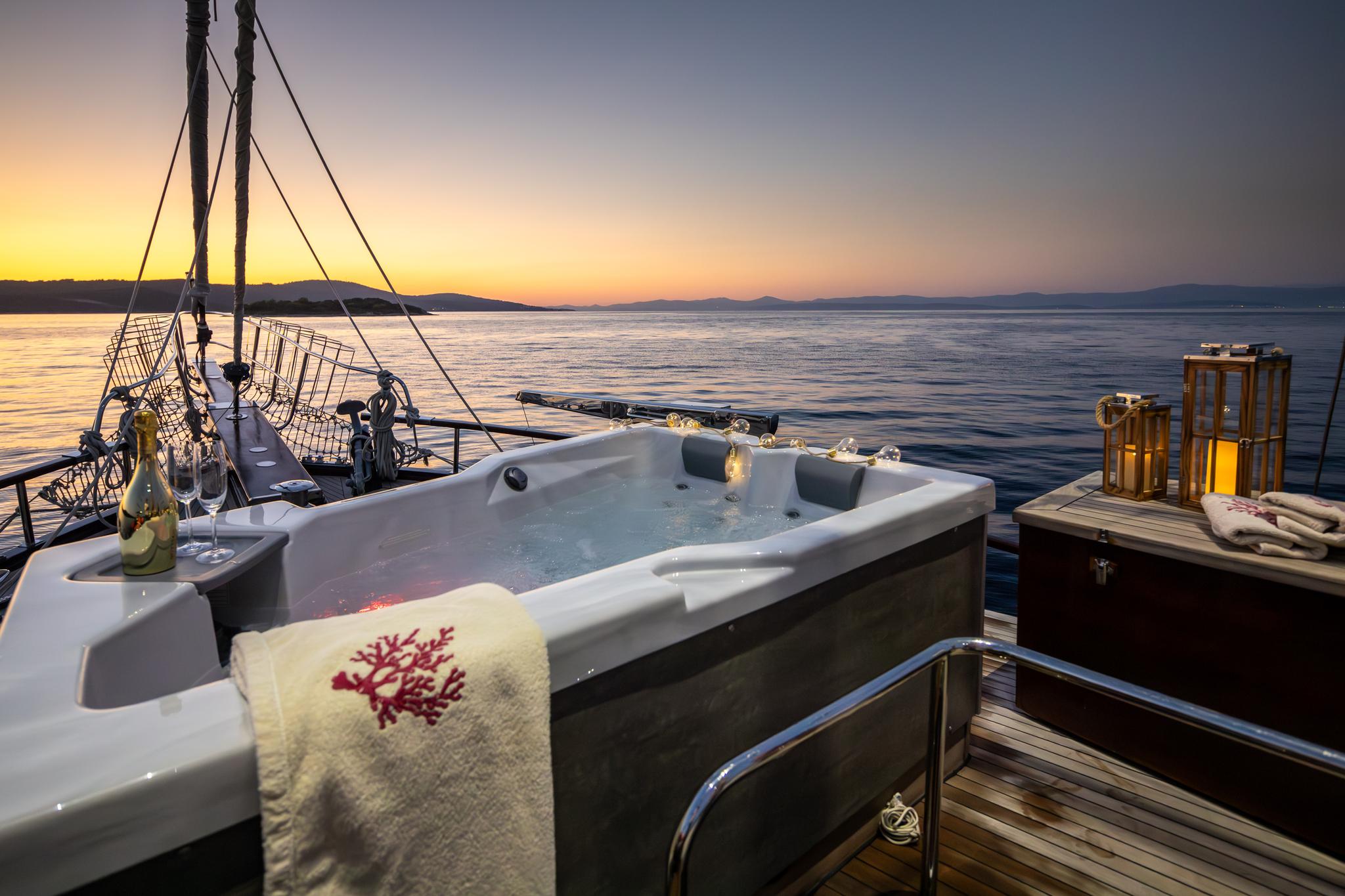 yacht jacuzzi with towels on deck at sunset with mountains