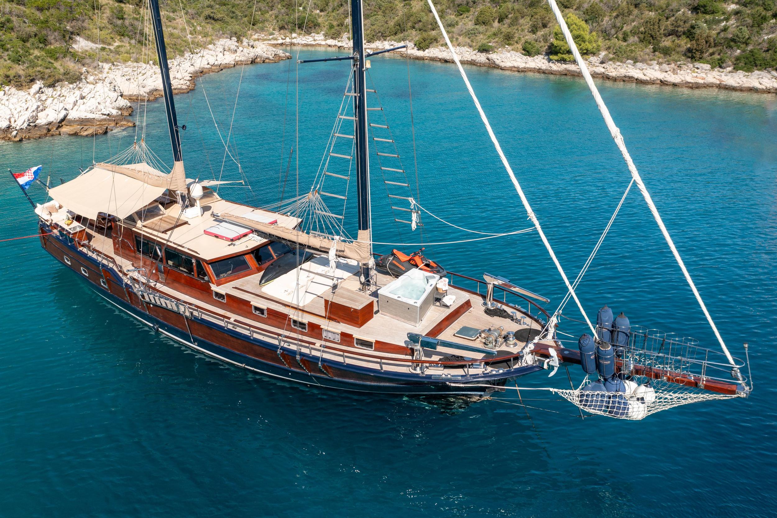 aerial view of wooden gulet yacht with two masts anchored in crystal clear turquoise Mediterranean bay