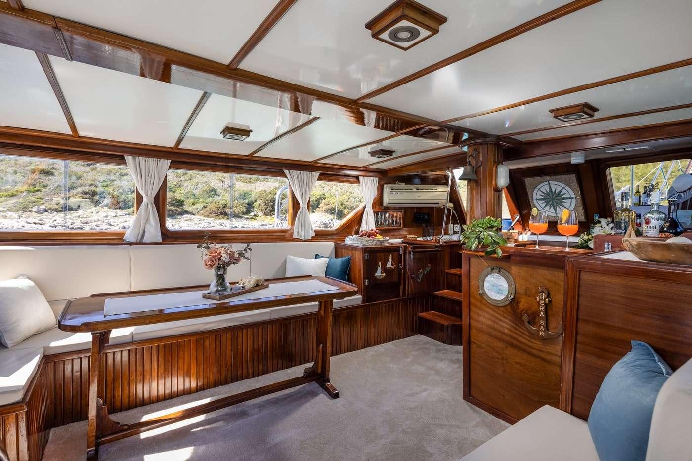 yacht salon interior with white cushioned seating, wooden dining table, and panoramic windows
