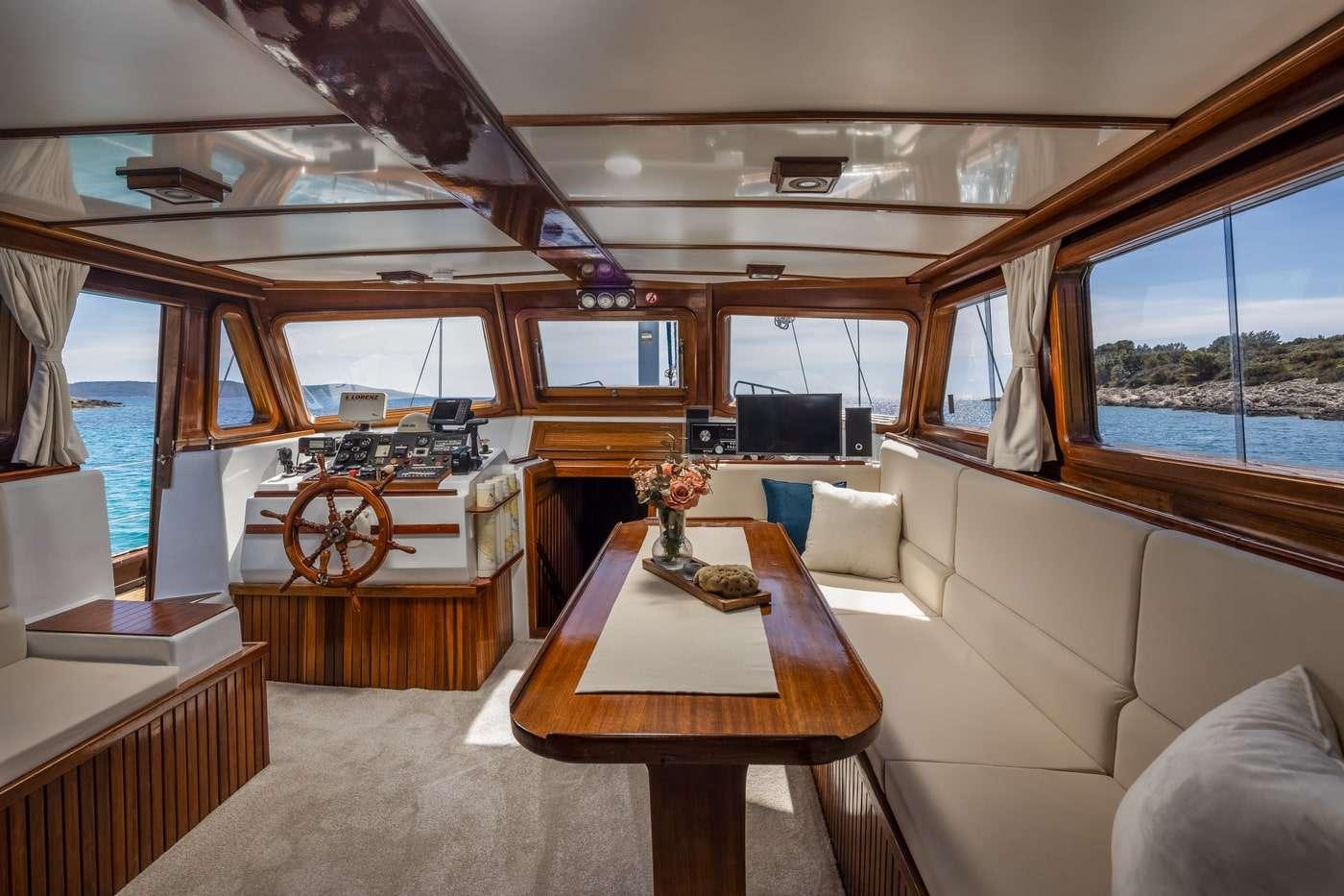 yacht wheelhouse interior with wooden helm station, navigation equipment, and white leather seating