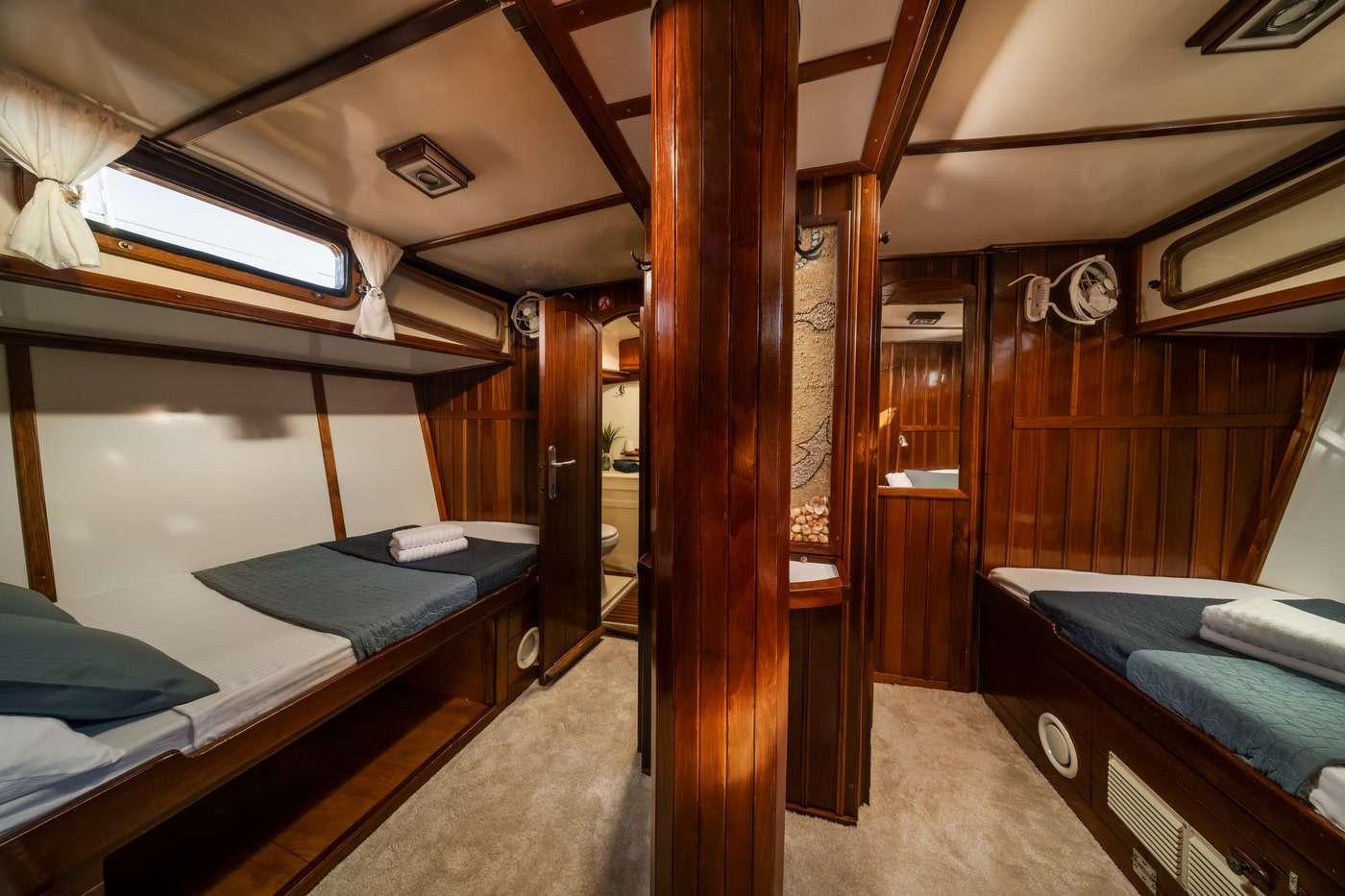 yacht guest cabin featuring twin bunk beds with navy bedding and polished wood interior