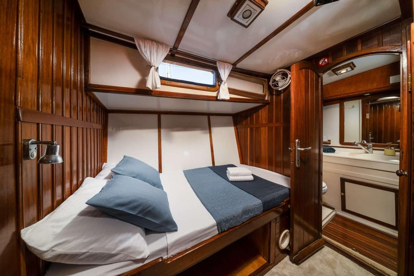 yacht guest cabin featuring twin beds with blue bedding and private ensuite bathroom