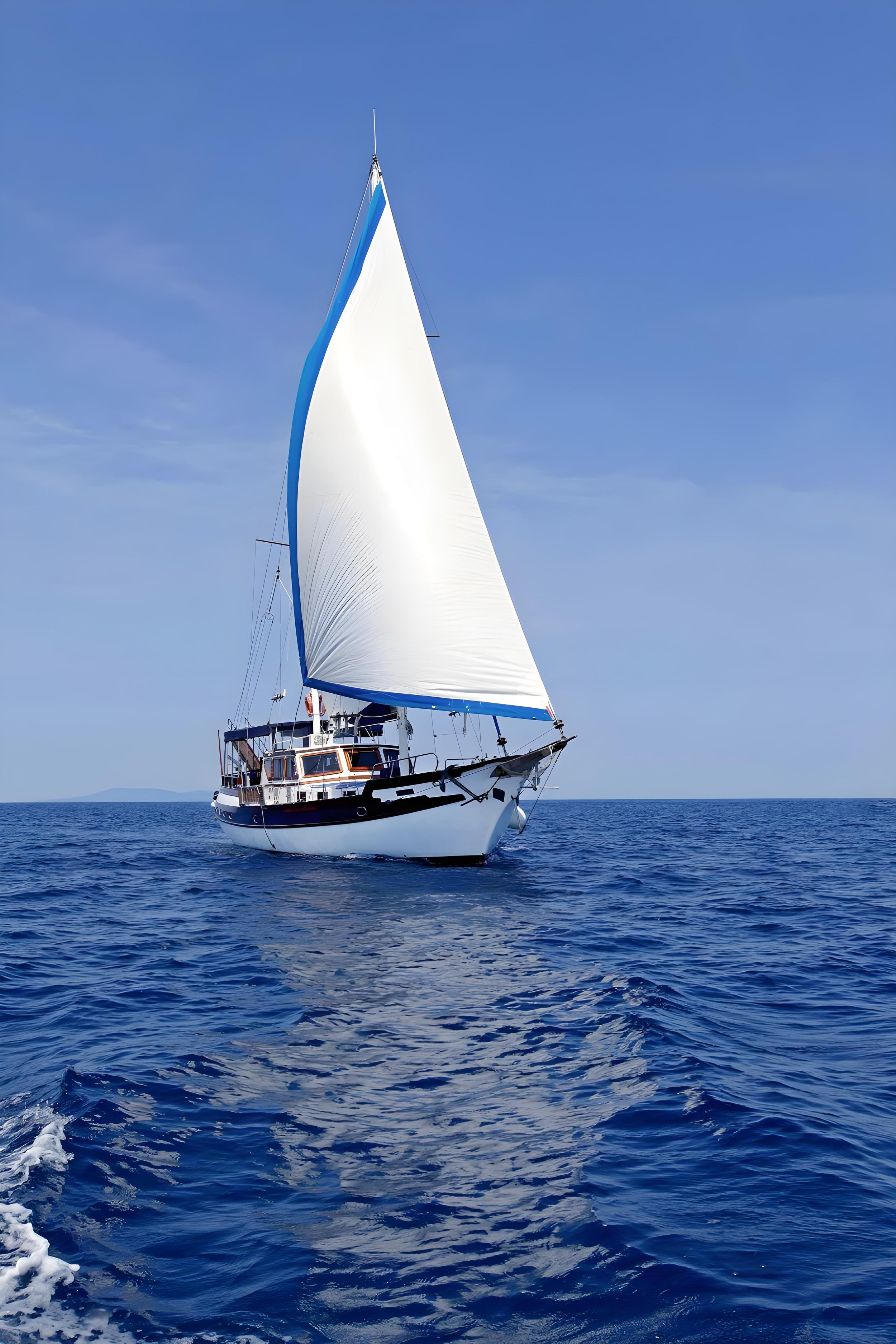 Traditional sailing gulet with large white mainsail with blue trim sailing on calm open sea