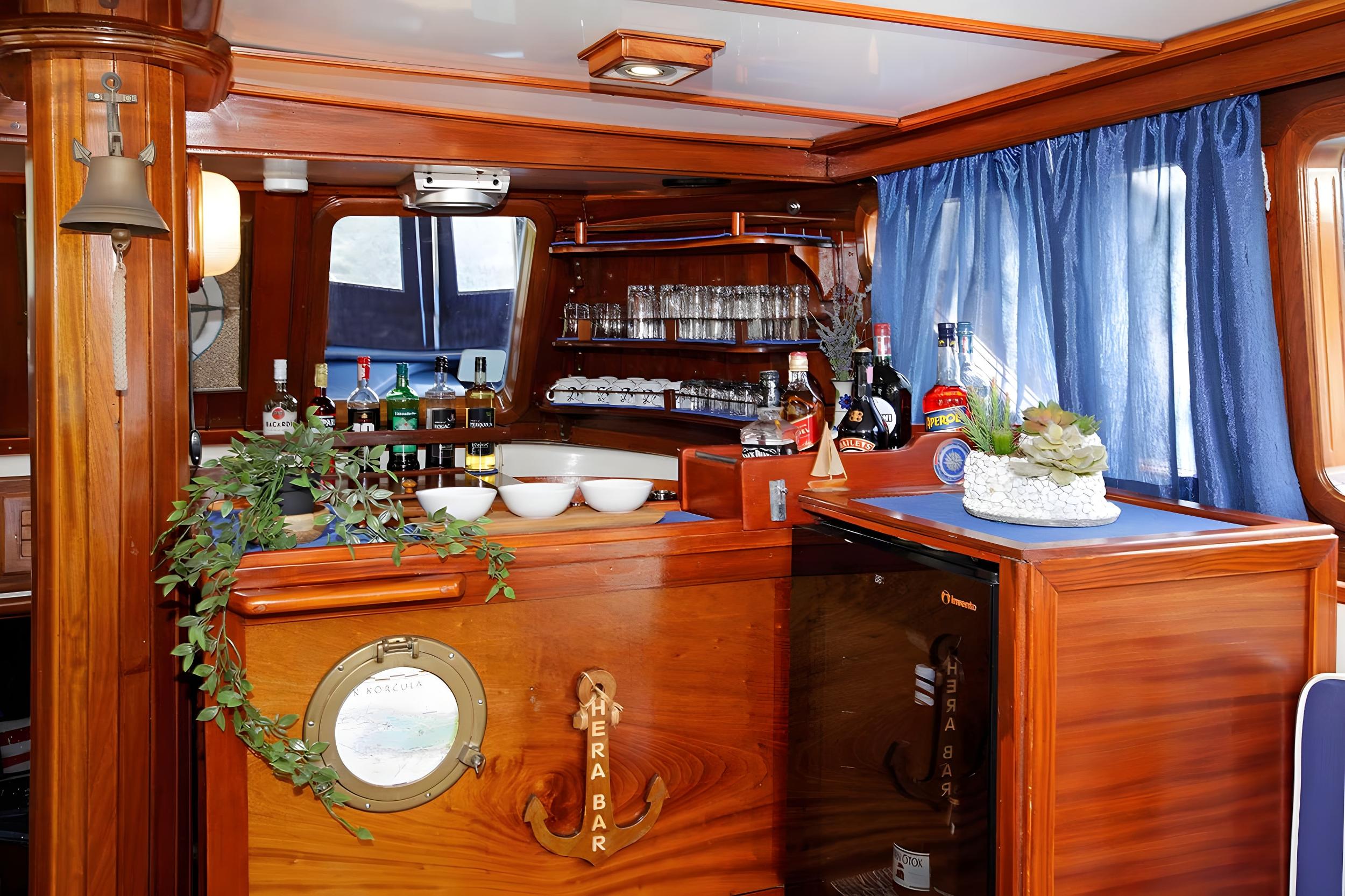 Hera Bar on gulet with stocked spirits shelves, glass rack, mini fridge and decorative porthole