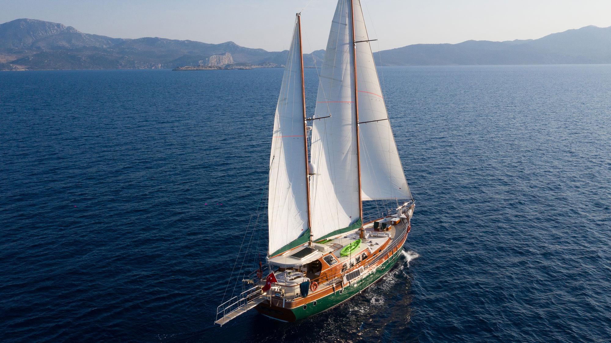 aerial view of traditional gulet yacht sailing with white sails deployed in blue Mediterranean waters