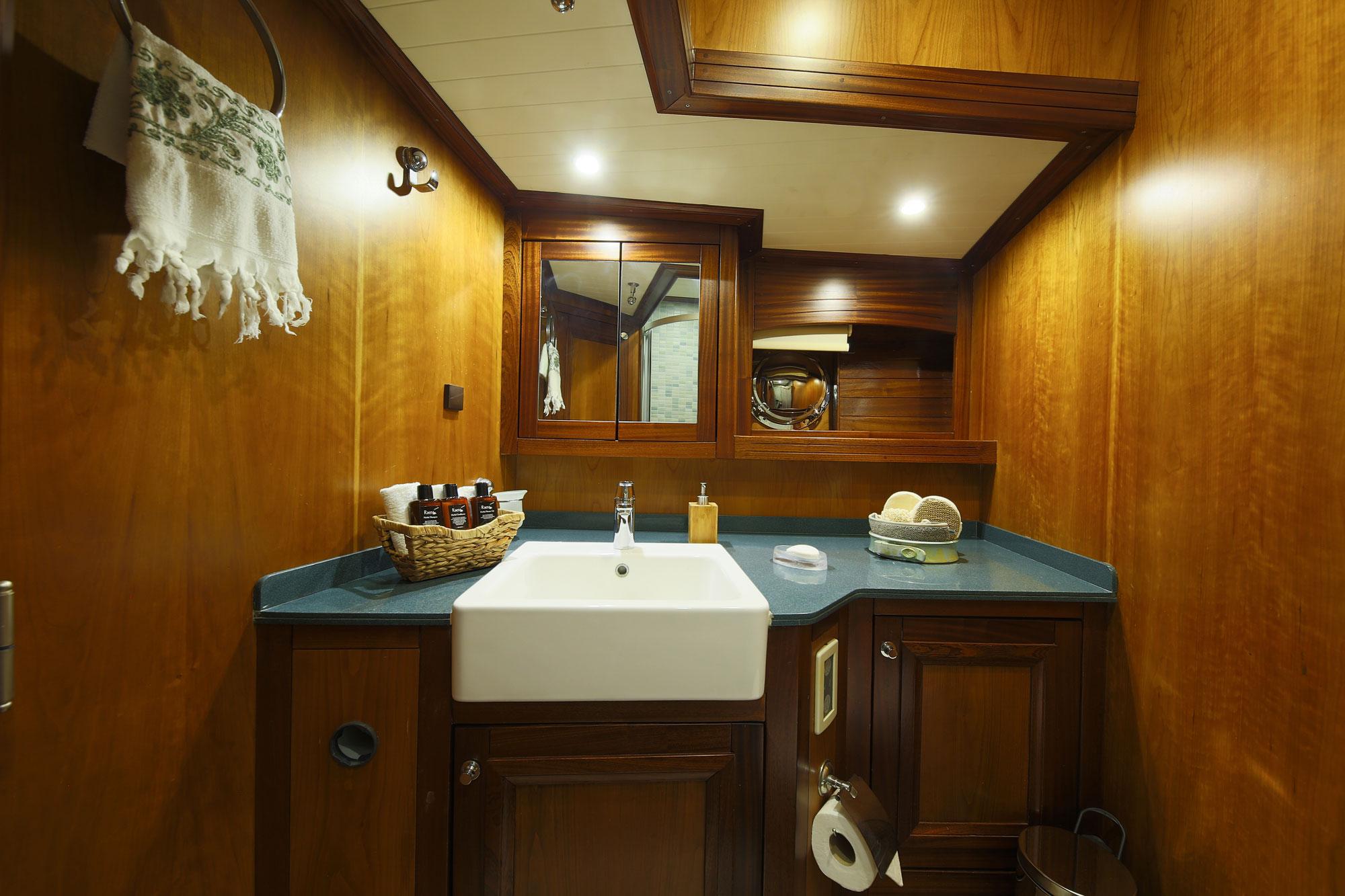 yacht bathroom featuring white rectangular sink, wooden cabinetry, and teal countertop