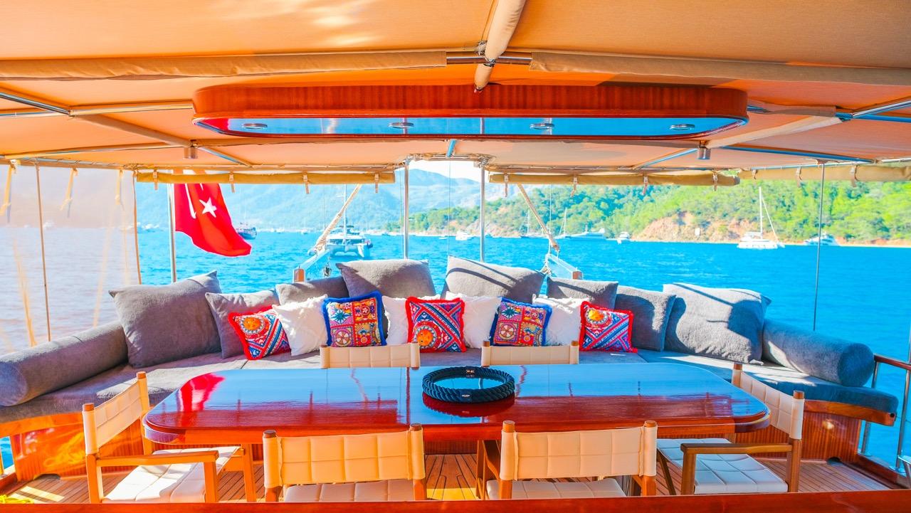 gulet aft deck lounge area with u-shaped seating, colorful cushions and Turkish flag