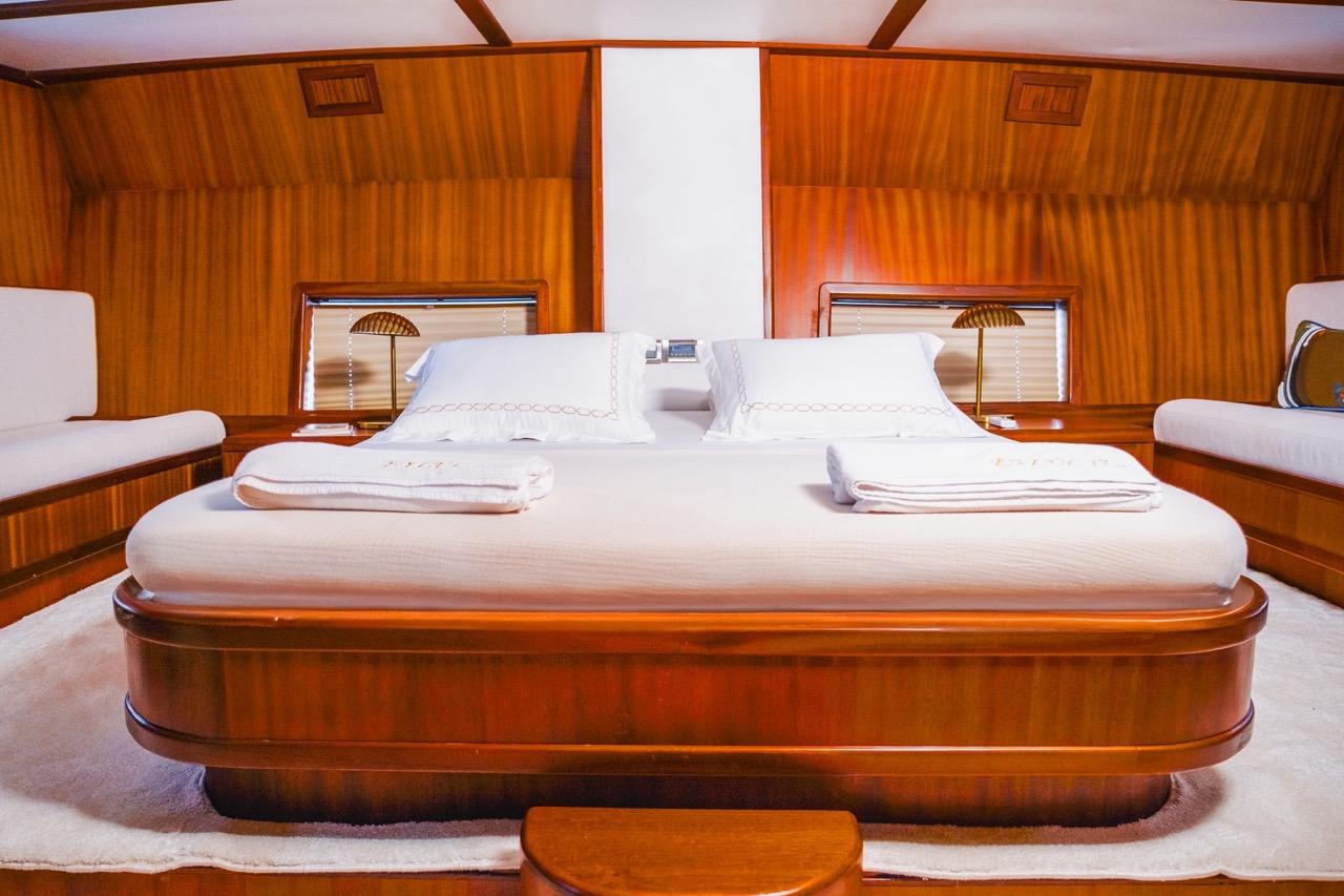 yacht guest cabin featuring double bed with white linens and rich wood paneling