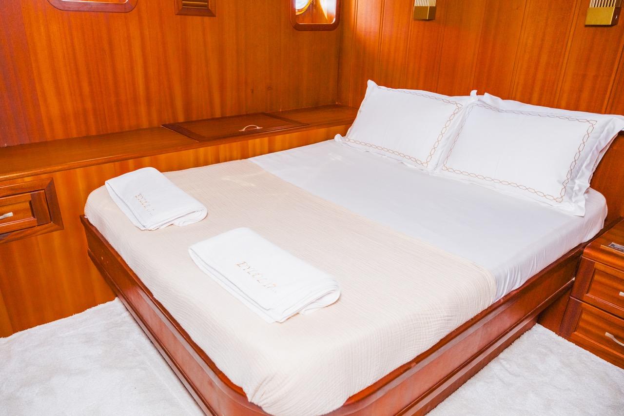 yacht guest cabin featuring double bed with white linens and decorative embroidered trim