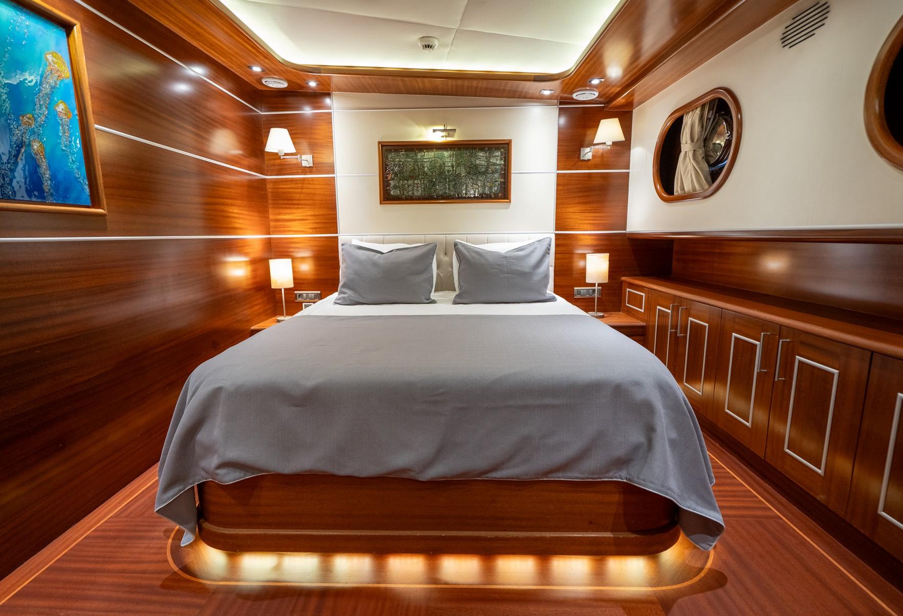 yacht guest cabin featuring double bed with gray bedding and rich wooden paneling