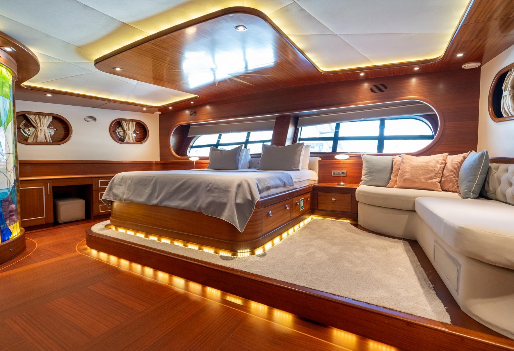 Master cabin interior featuring king bed with LED lighting, built-in seating, and panoramic windows