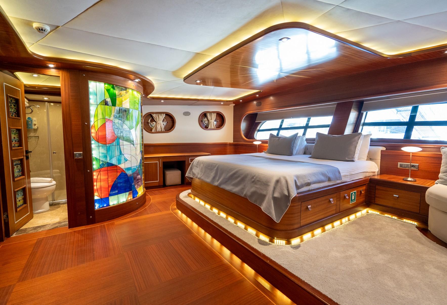 Master cabin with king bed, curved stained glass column, wood paneling and en-suite bathroom