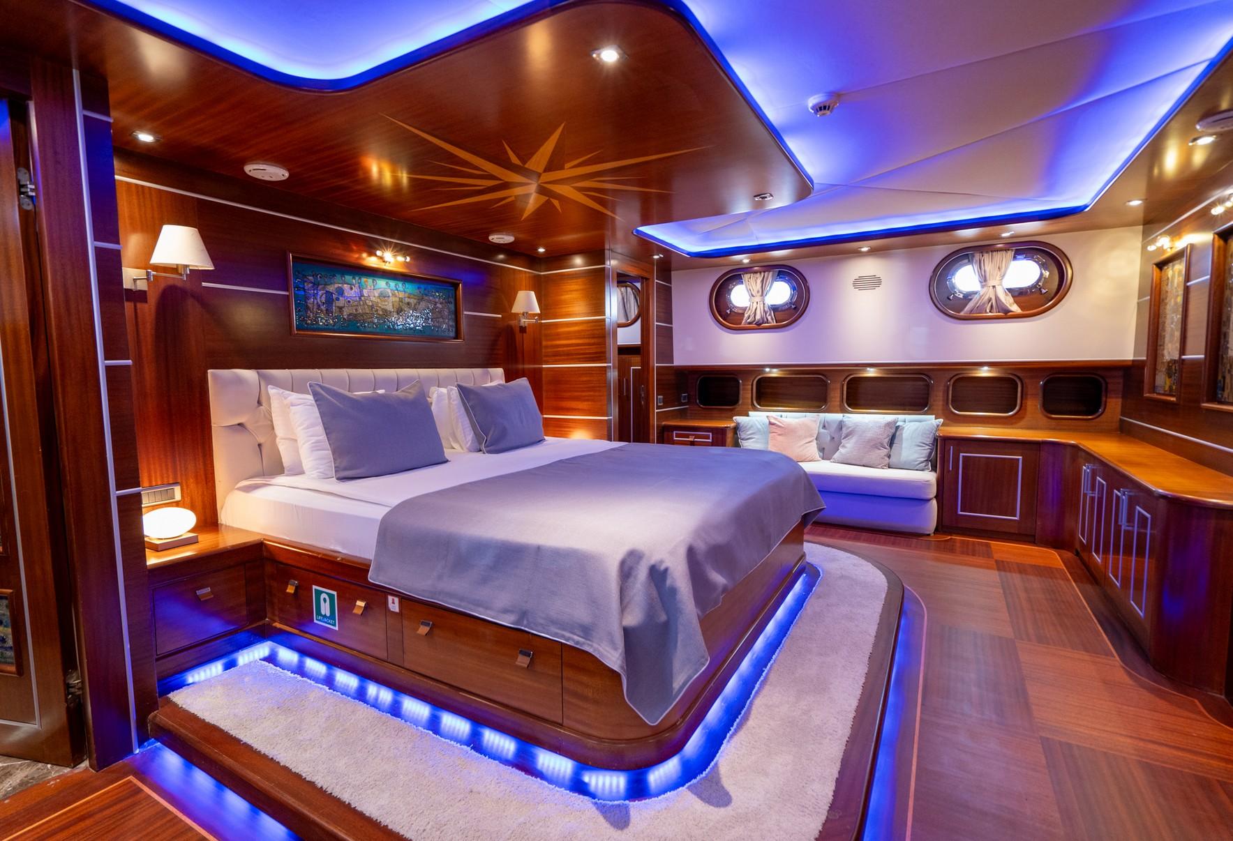 yacht master cabin with king bed, wood paneling, LED ceiling lighting and portholes