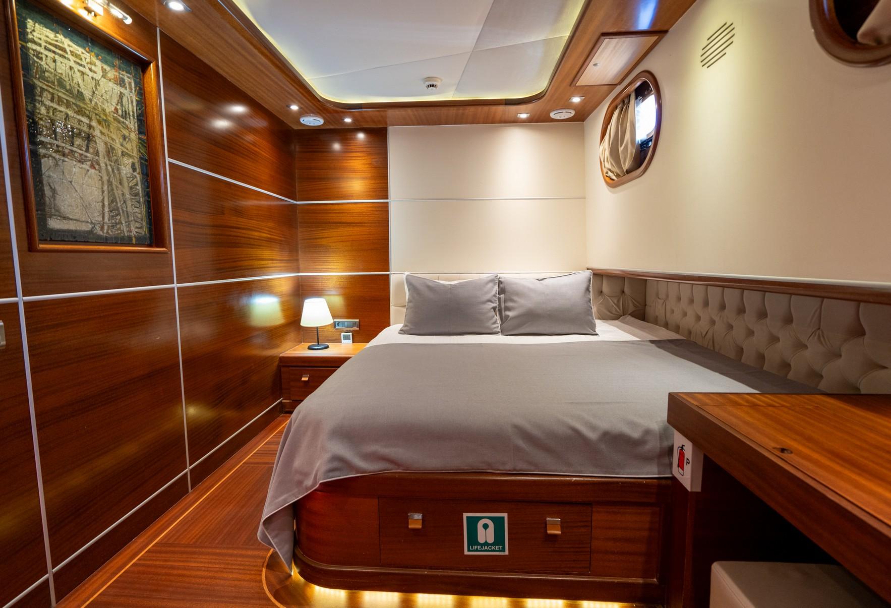 yacht guest cabin featuring double bed with grey linens and beige tufted headboard