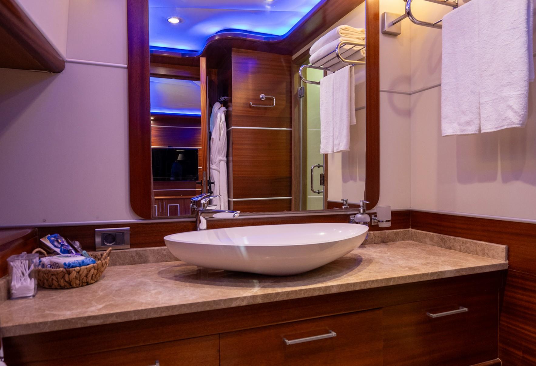 luxury yacht bathroom featuring white oval vessel sink on marble countertop with vanity storage