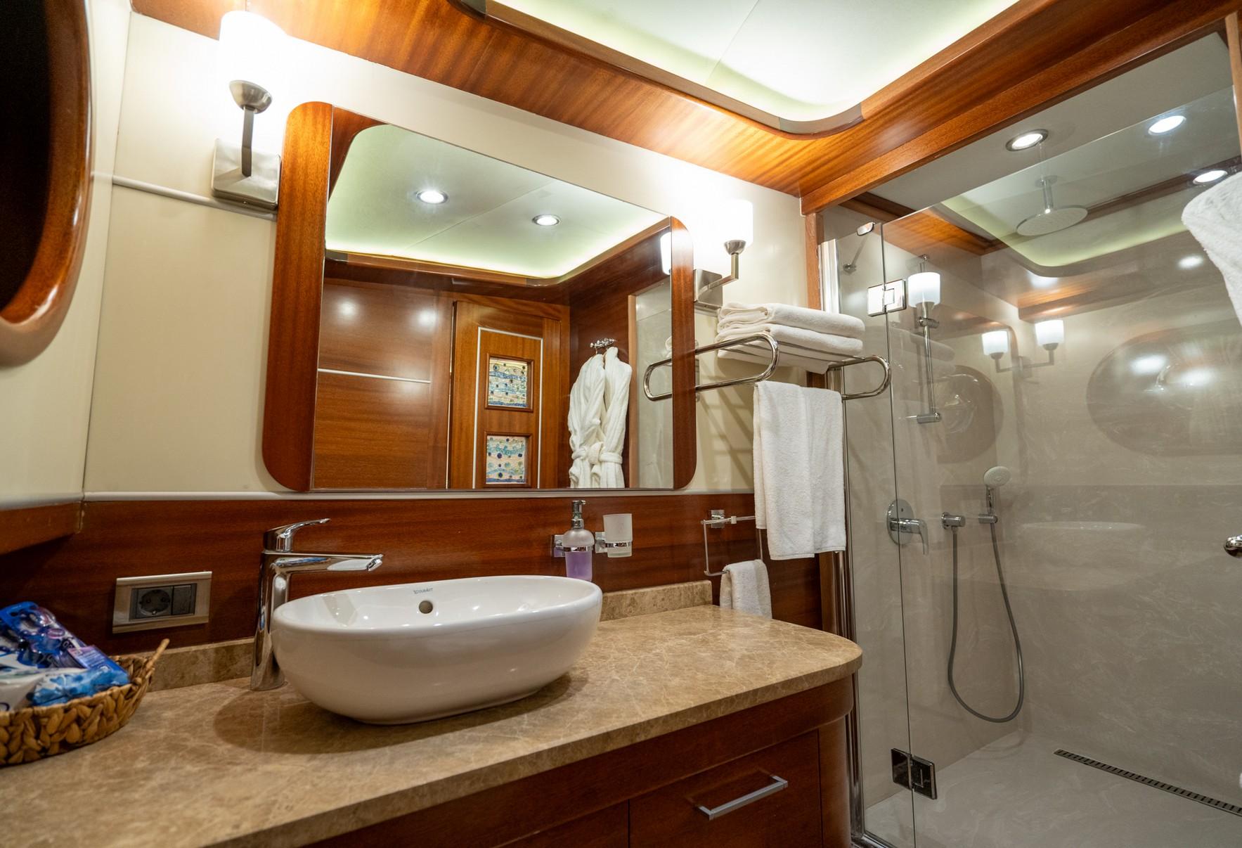 luxury yacht bathroom featuring white vessel sink on marble counter and glass-enclosed shower