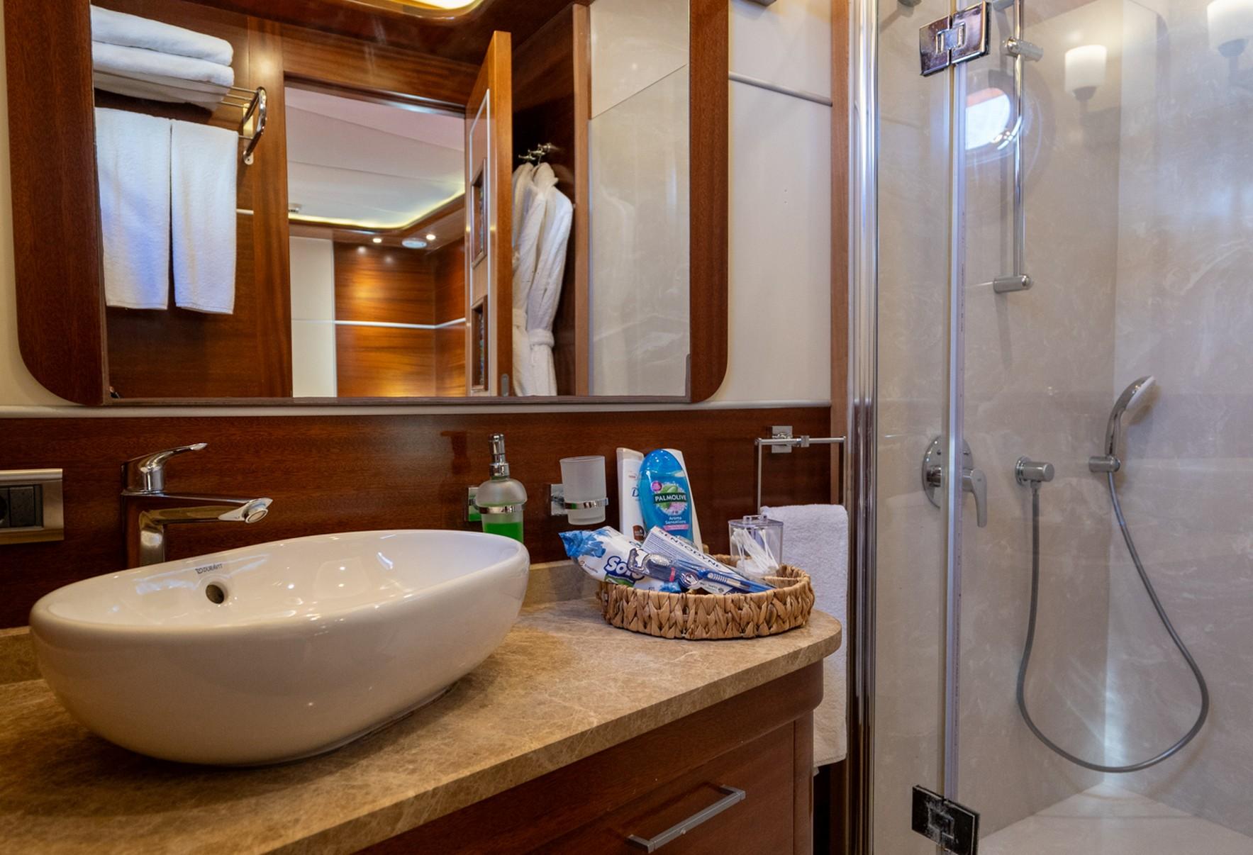 yacht bathroom featuring white vessel sink on stone countertop with glass shower enclosure