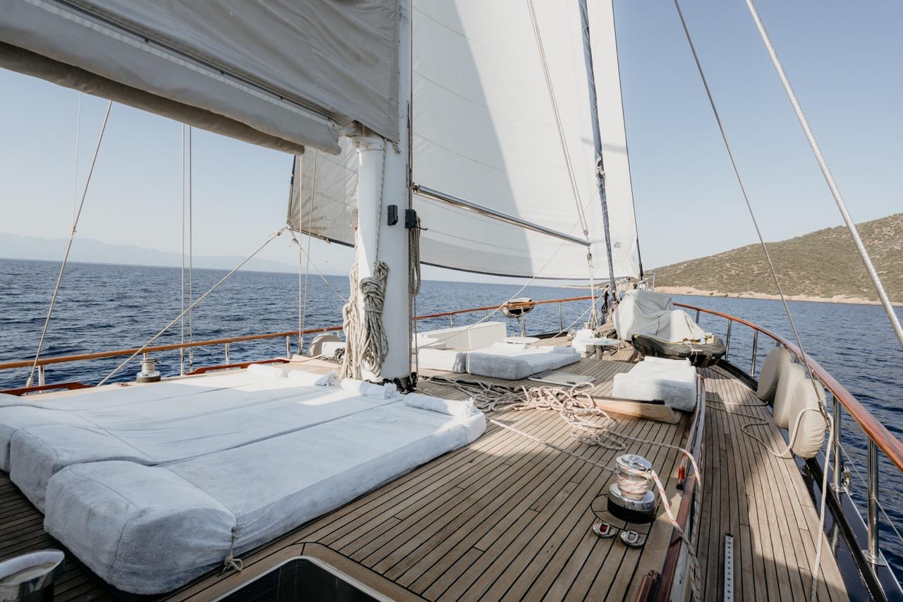 sailing yacht teak deck with white cushioned seating area and mast rigging