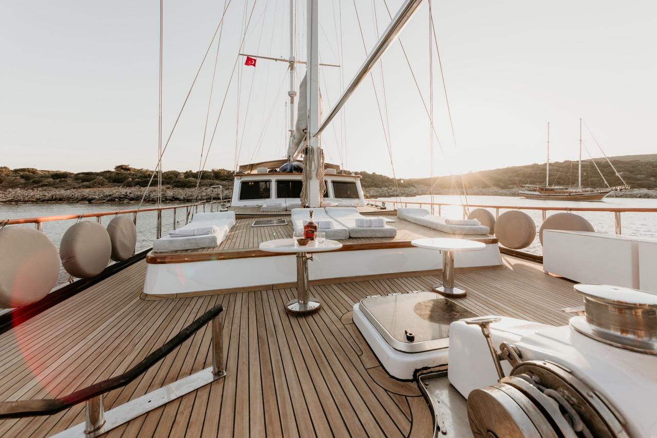gulet main deck dining area with white bench seating, round table and teak decking