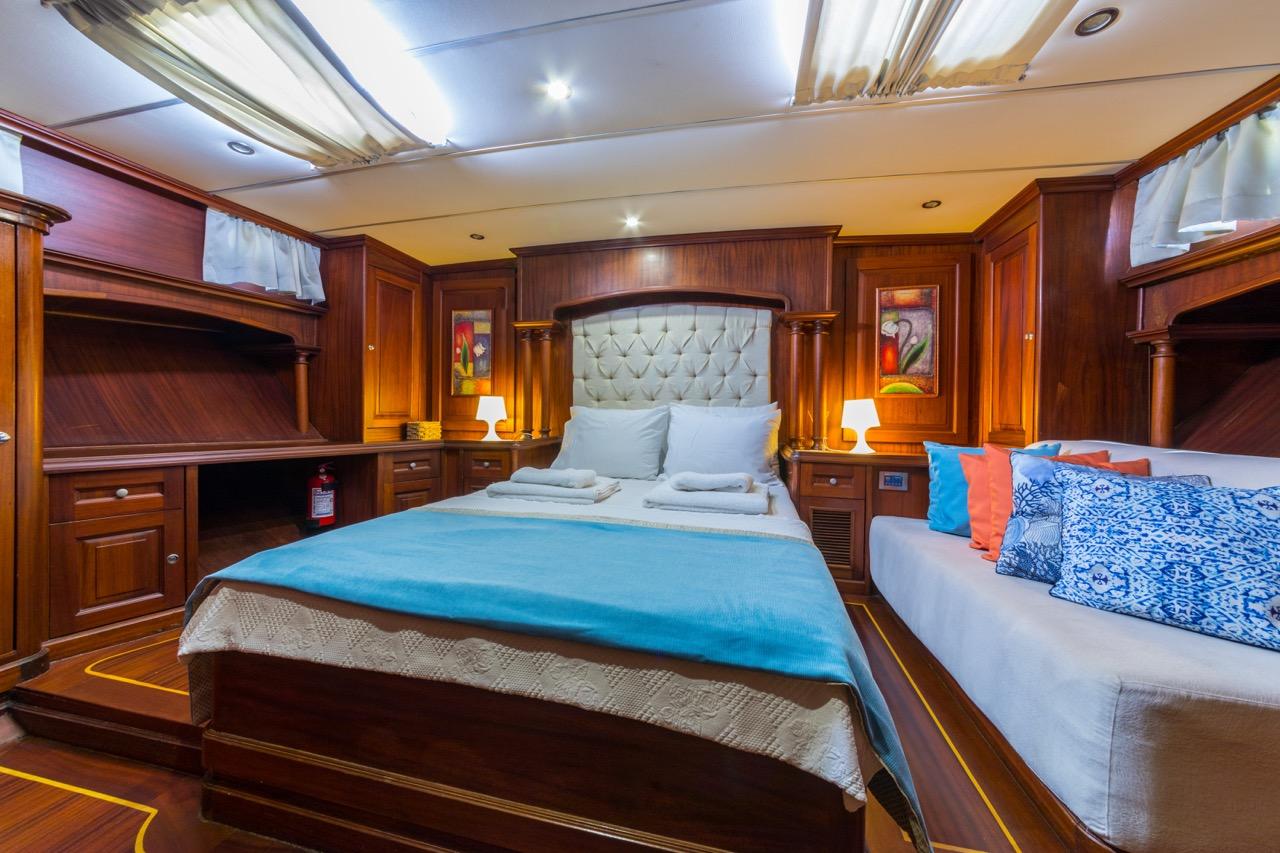 yacht cabin interior with double bed, tufted headboard, built-in wardrobes and reading lights