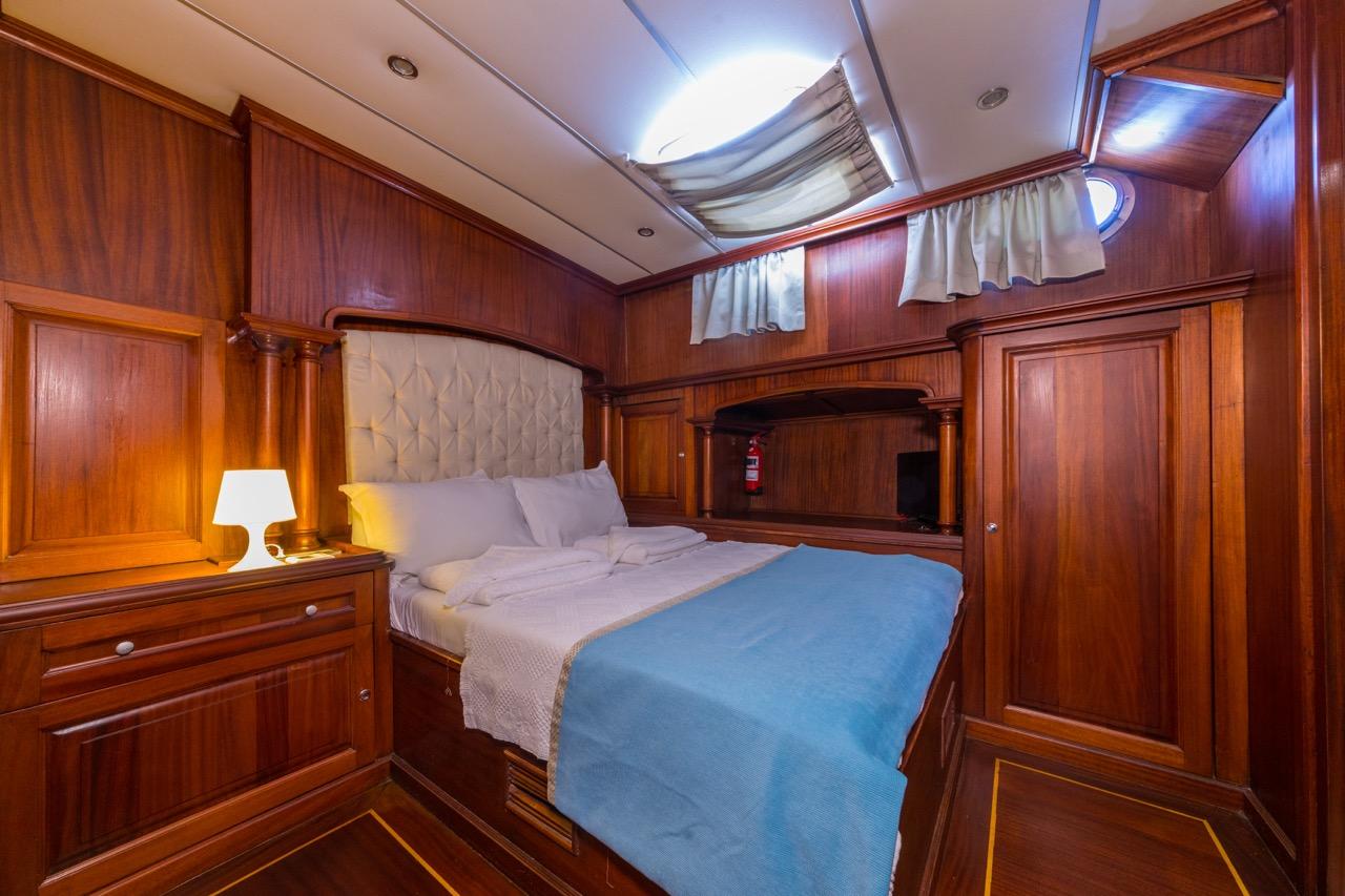 yacht guest cabin featuring double bed with white diamond-tufted headboard and rich wood paneling