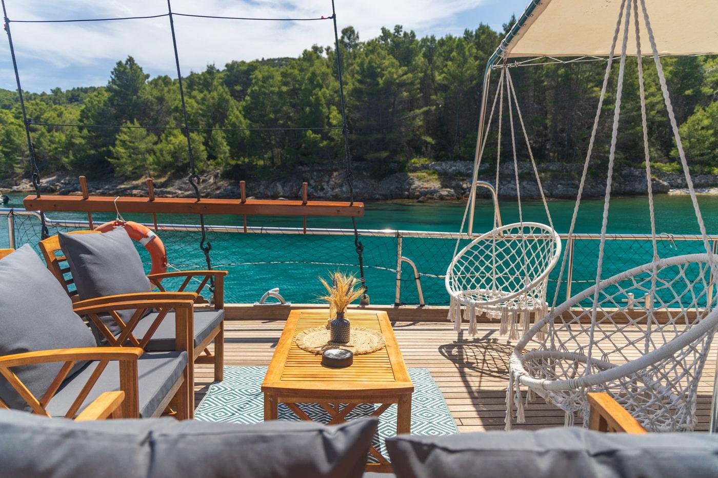 yacht deck lounge area with teak furniture overlooking turquoise Mediterranean waters