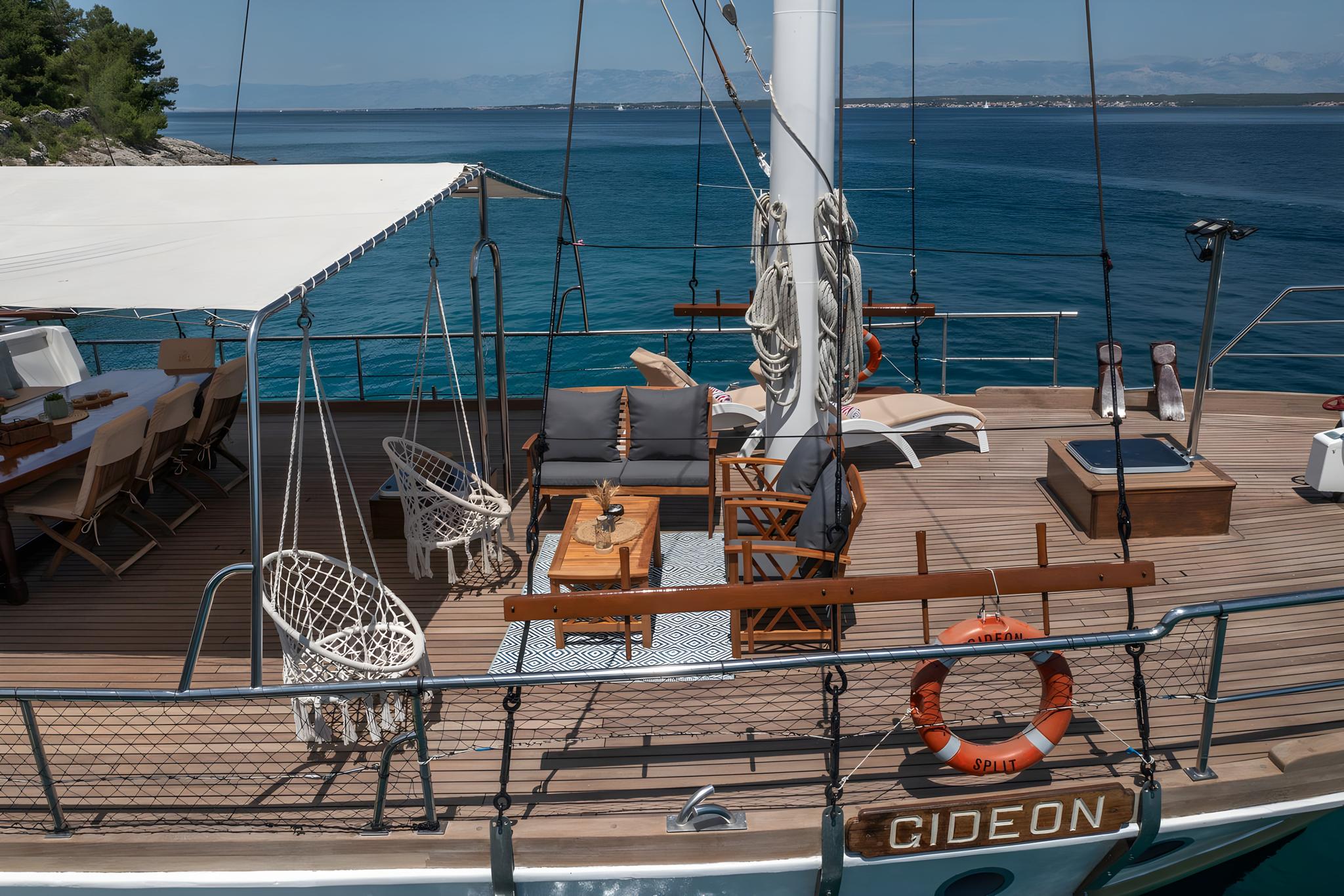 Gideon gulet main deck featuring hanging wicker chairs and teak furniture