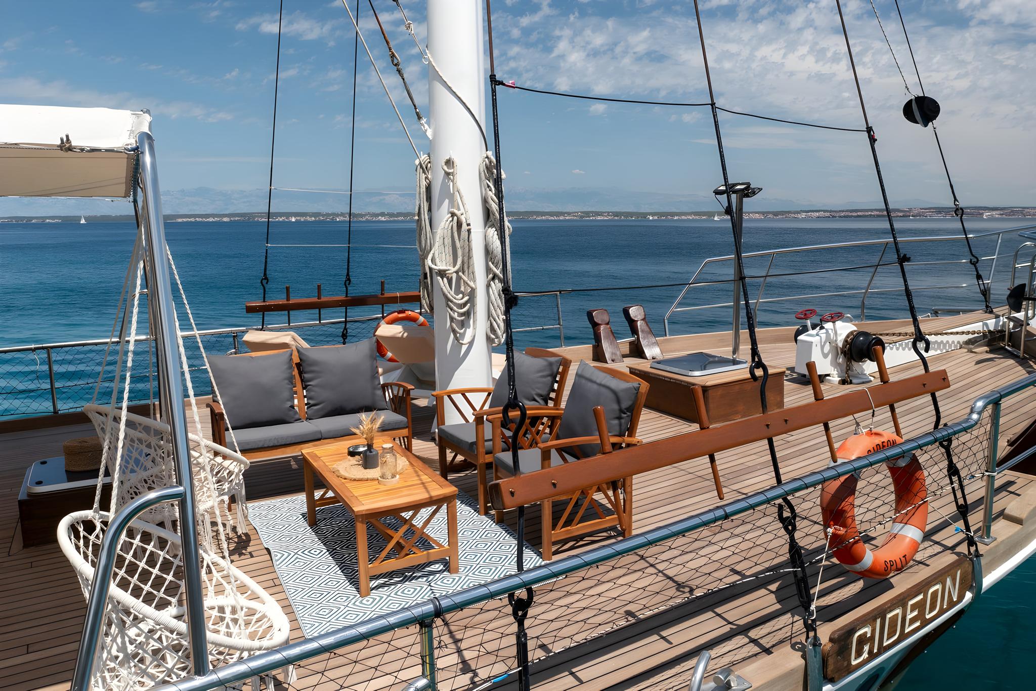 luxury sailing yacht main deck with teak furniture and geometric rug