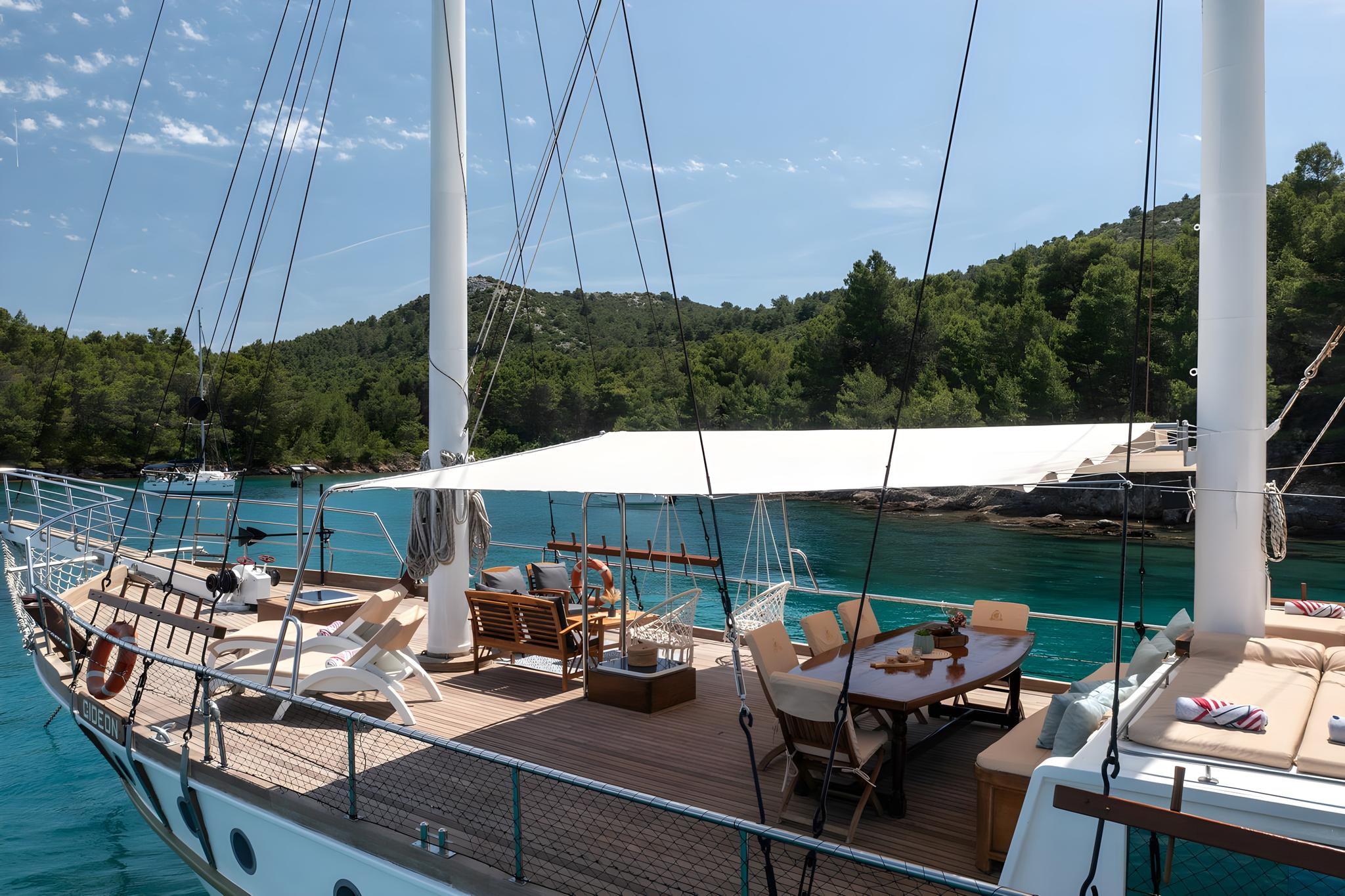 Gulet aft deck dining area with canvas awning anchored in crystal clear turquoise waters