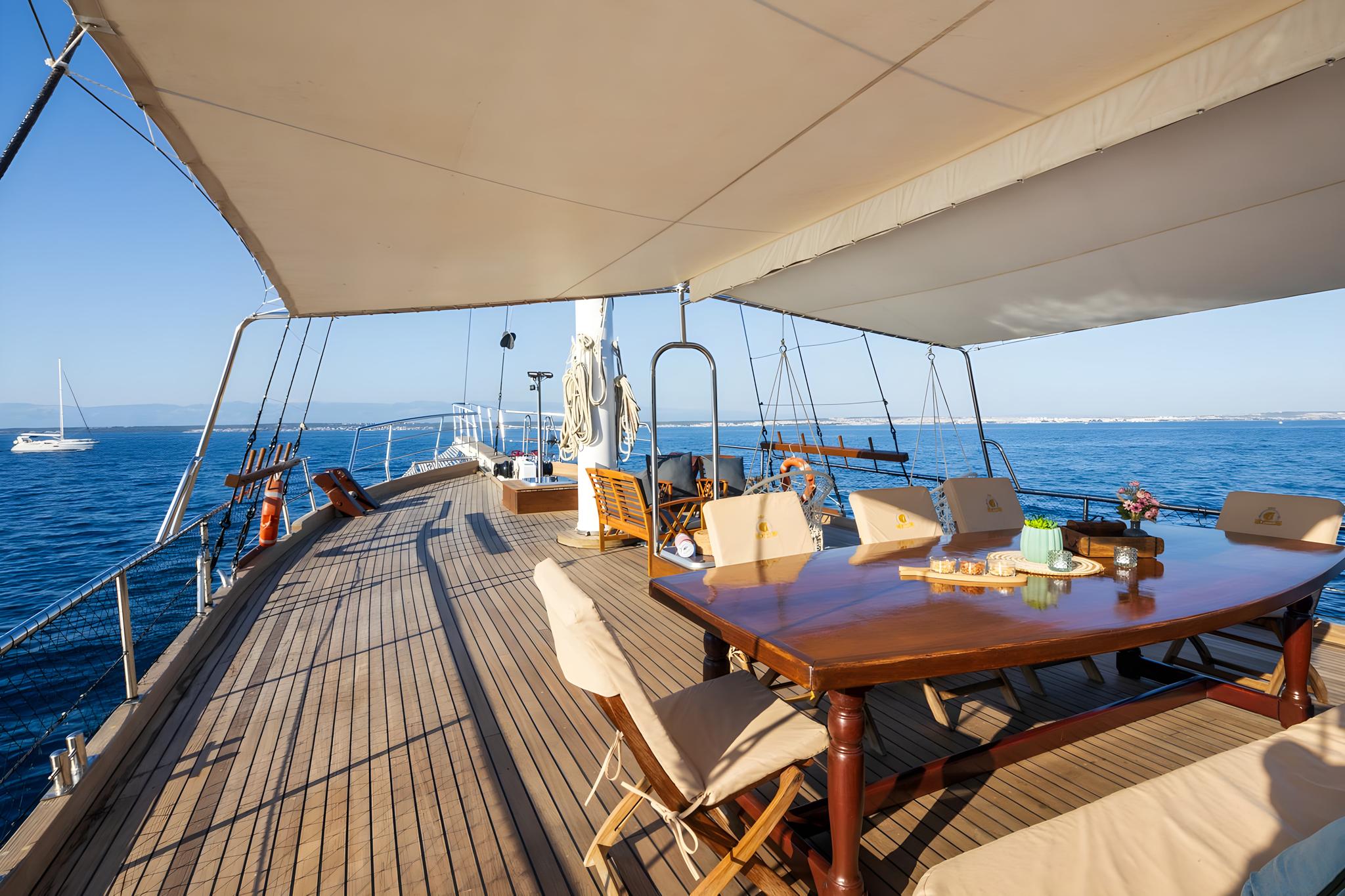 Traditional yacht main deck with wooden dining table under cream awning