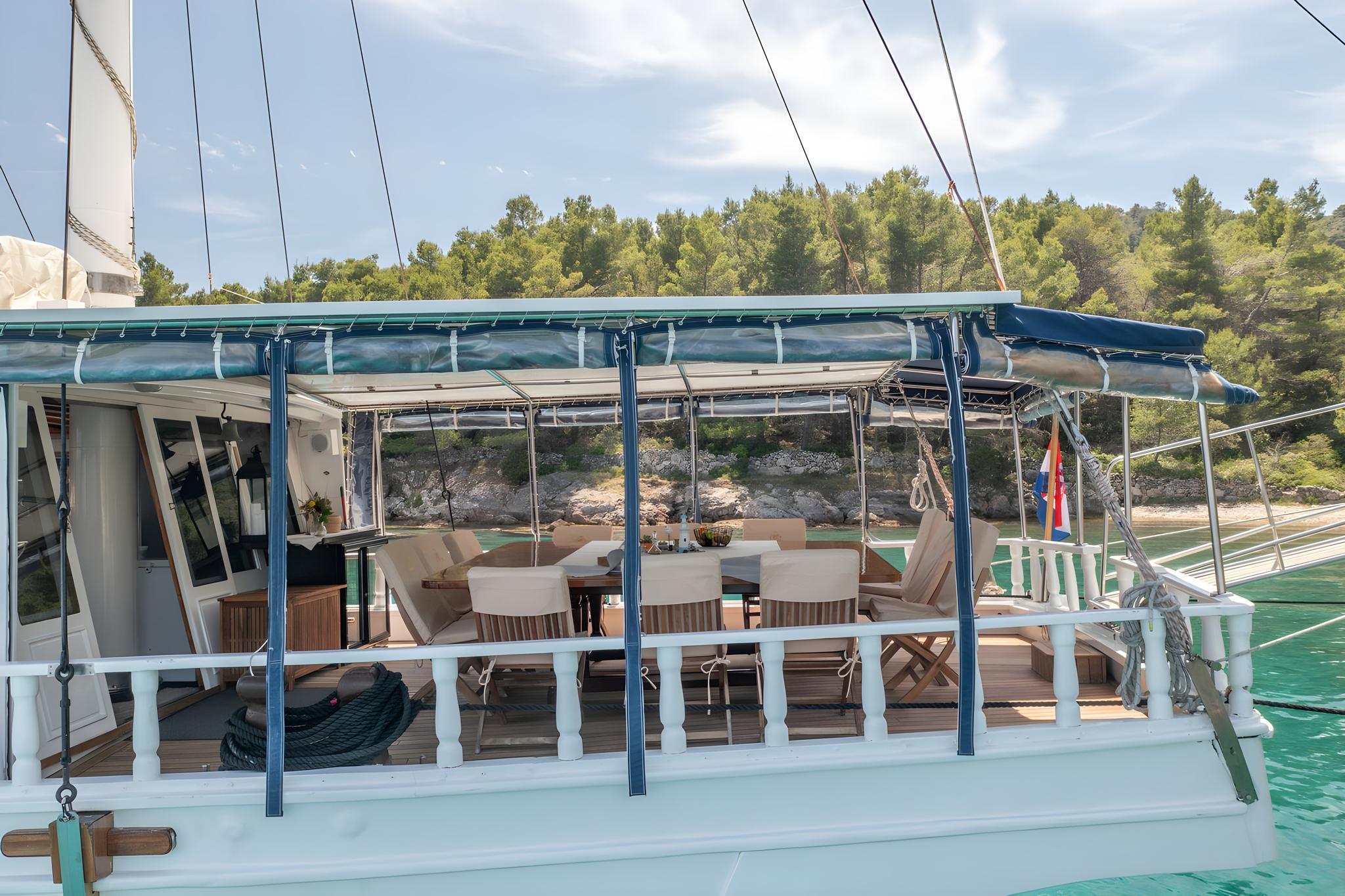 Gulet aft deck dining area with blue canvas awning and wooden table