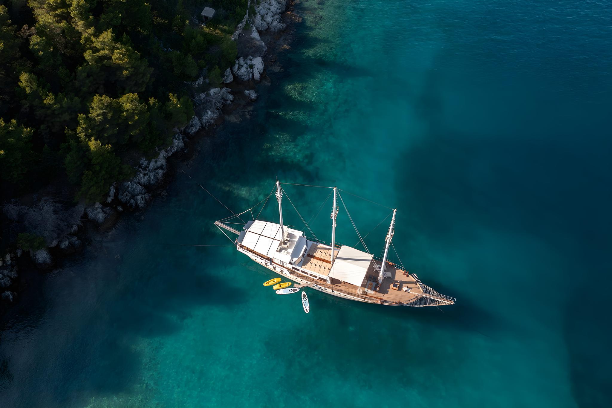 Aerial view of wooden gulet yacht anchored in crystal clear turquoise waters