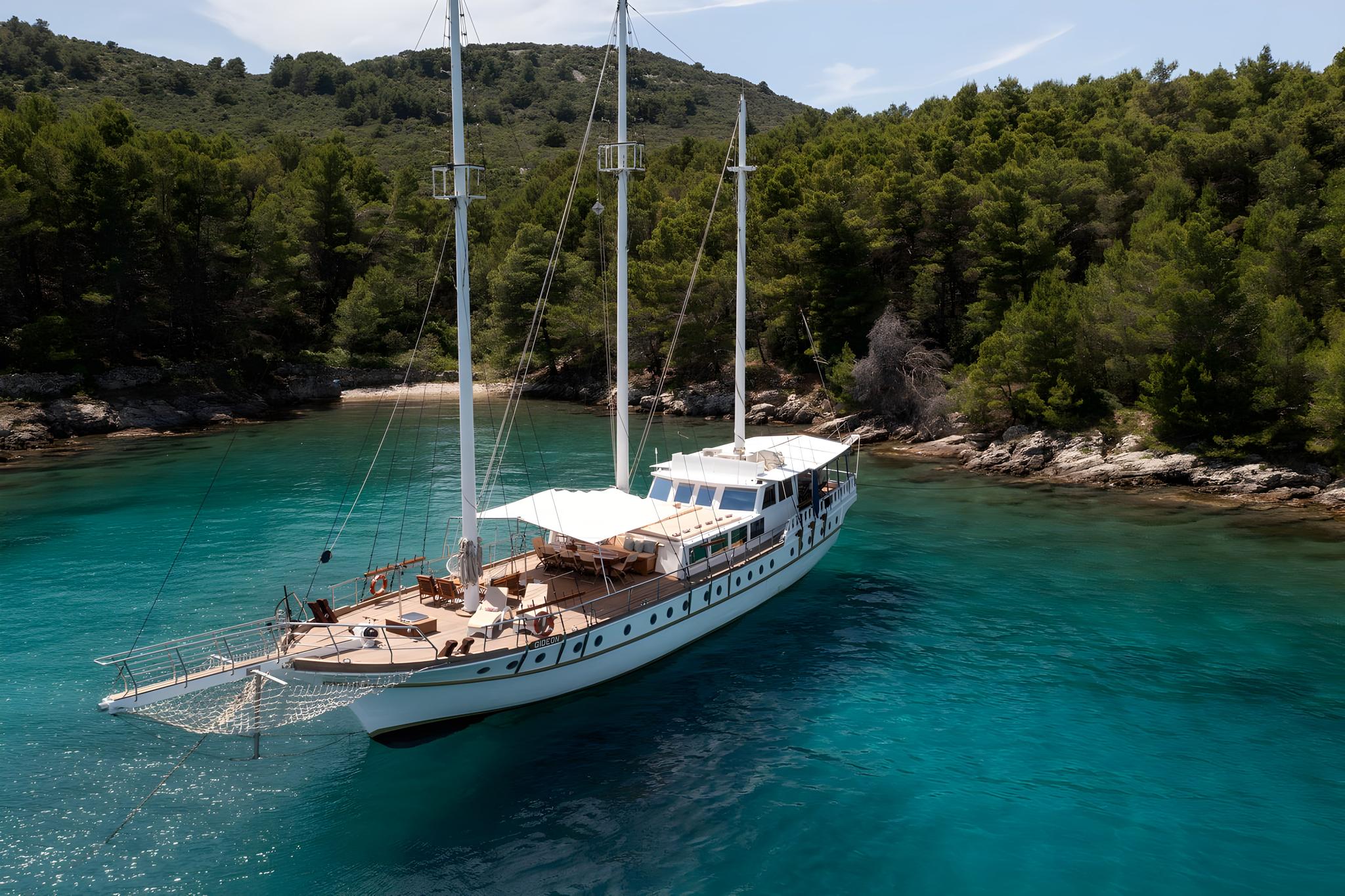 aerial view white gulet yacht anchored crystal clear turquoise bay forested coastline