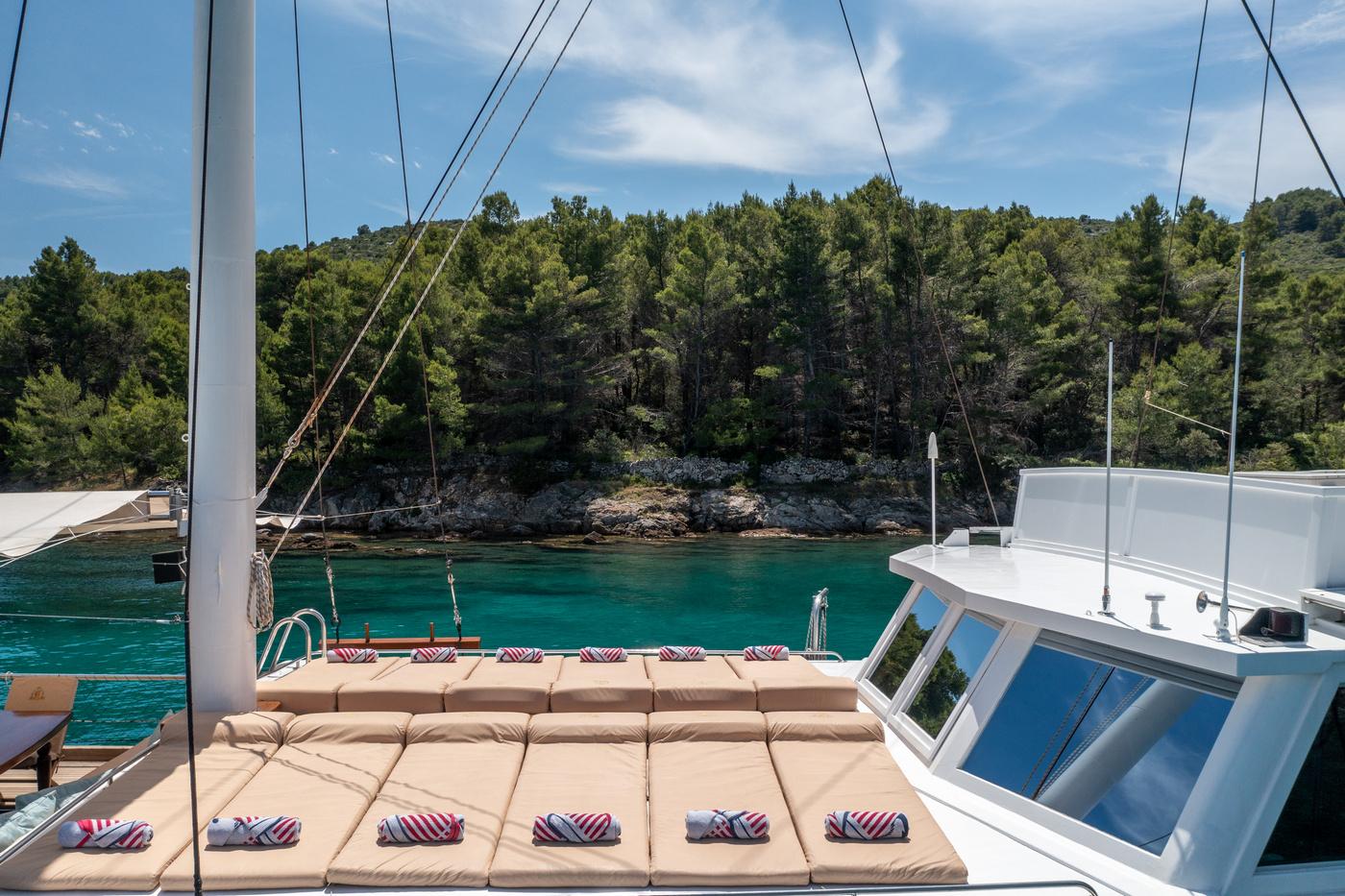 yacht aft deck with beige cushioned seating area overlooking turquoise Mediterranean bay