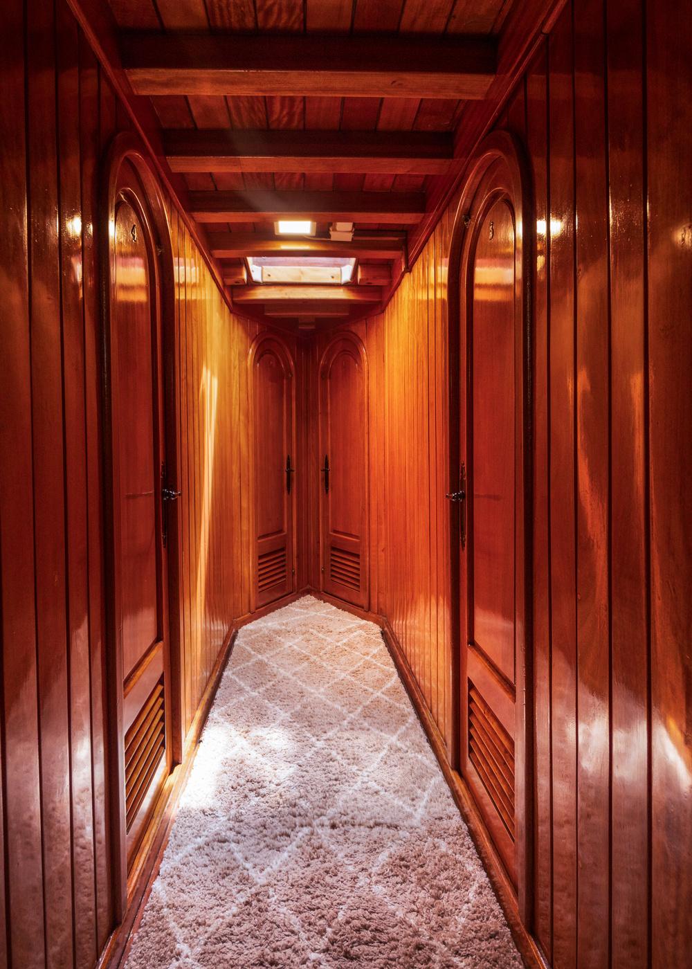 yacht interior corridor with rich wood paneling, exposed beams, and plush carpet
