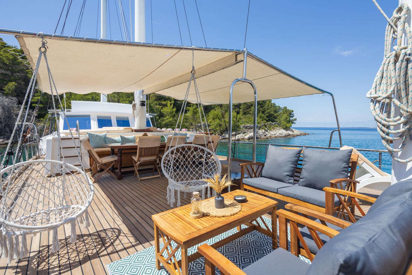 Gulet aft deck with teak furniture, grey cushions, hammock and beige sun awning