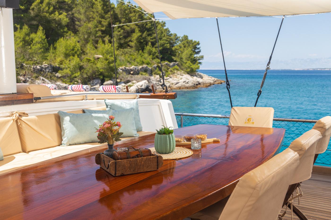 yacht aft deck dining table with built-in seating overlooking Mediterranean coastline