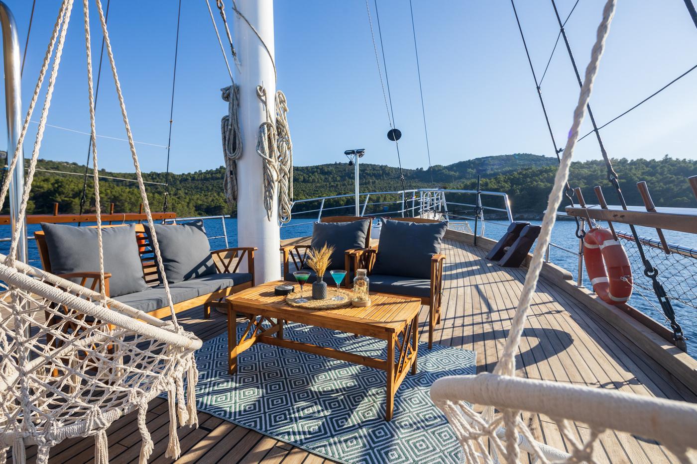 gulet forward deck with teak furniture, rope hammock, and outdoor seating lounge