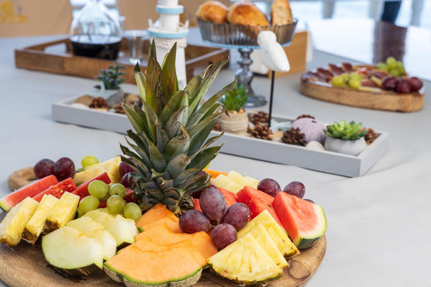 elaborate fresh fruit platter with pineapple centerpiece and assorted breakfast items on yacht dining table
