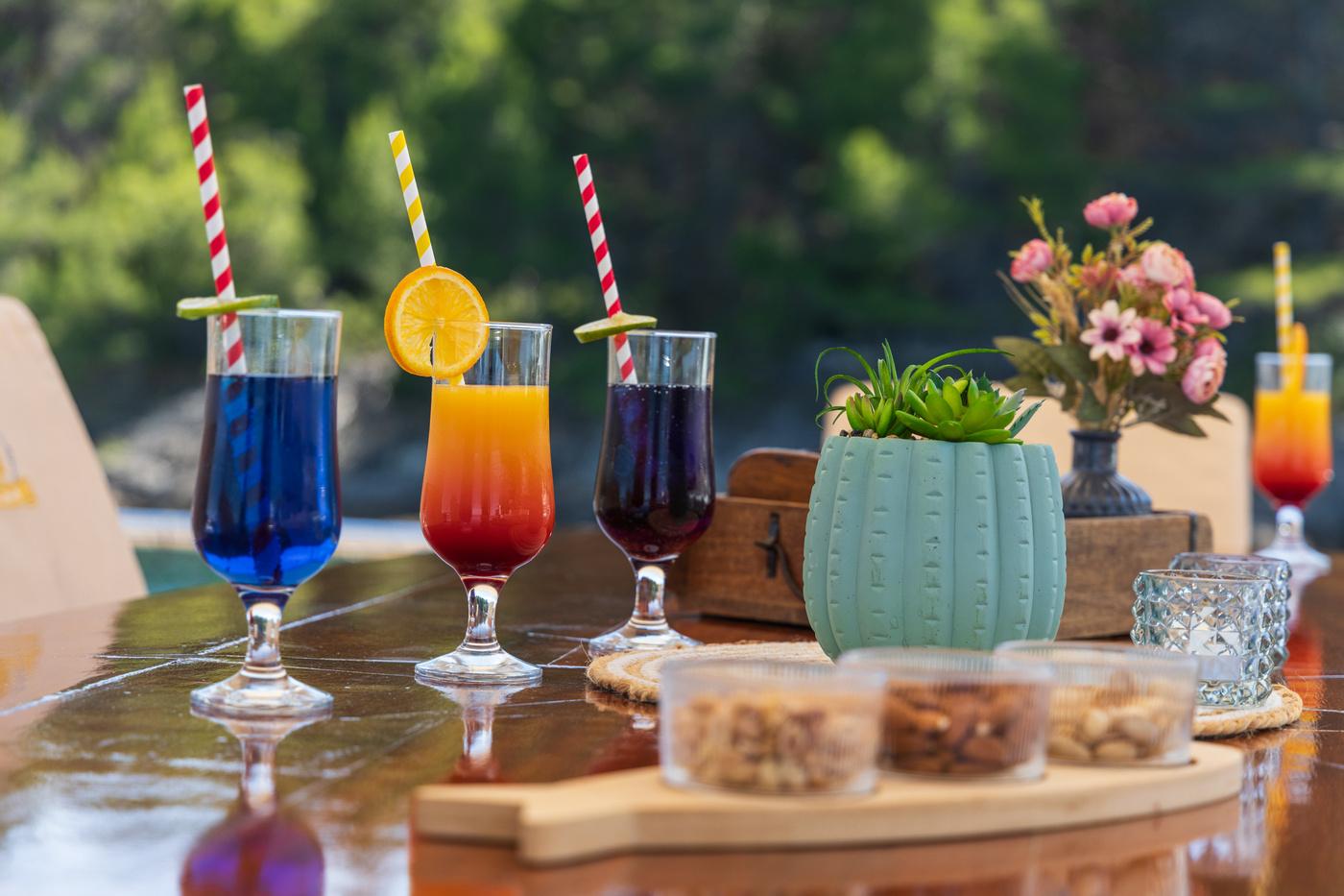 Colorful cocktails with straws served on yacht dining table with decorative plants